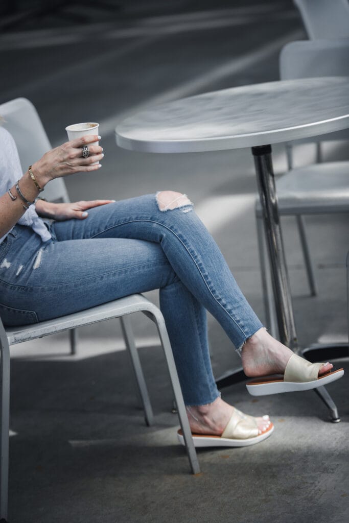 Heather Anderson wearing ripped jeans and gold slides