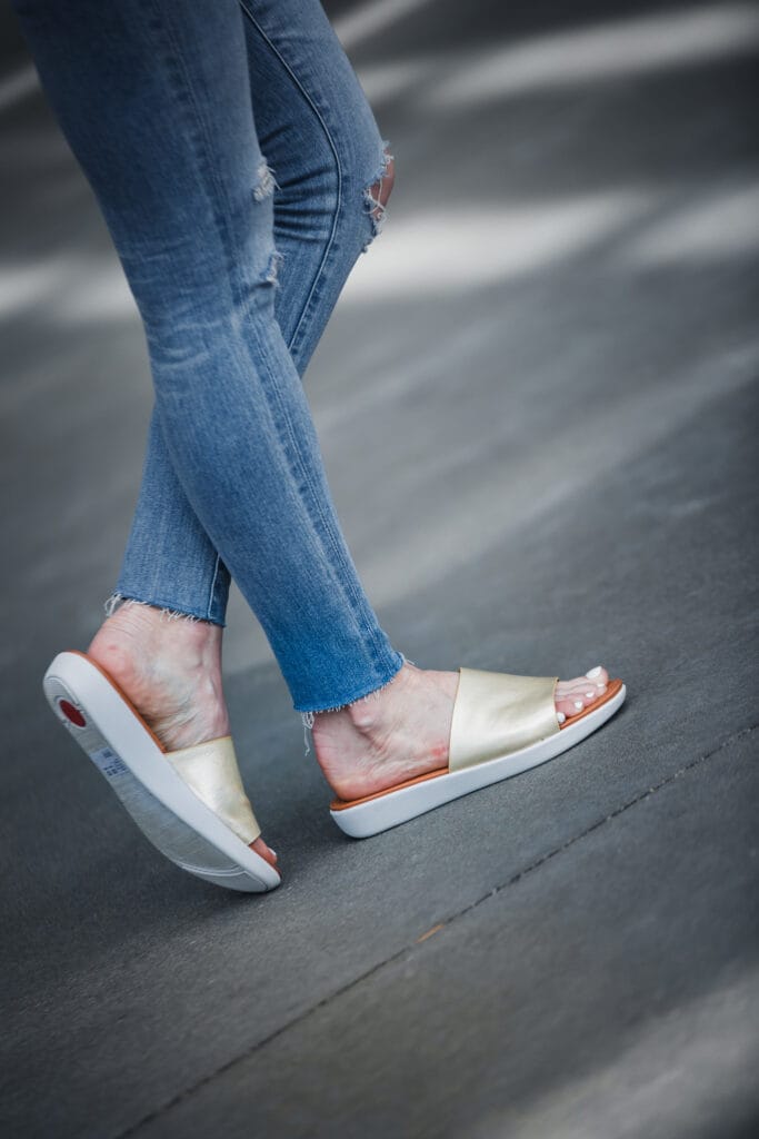 Ripped jeans, gold slides, and white tee