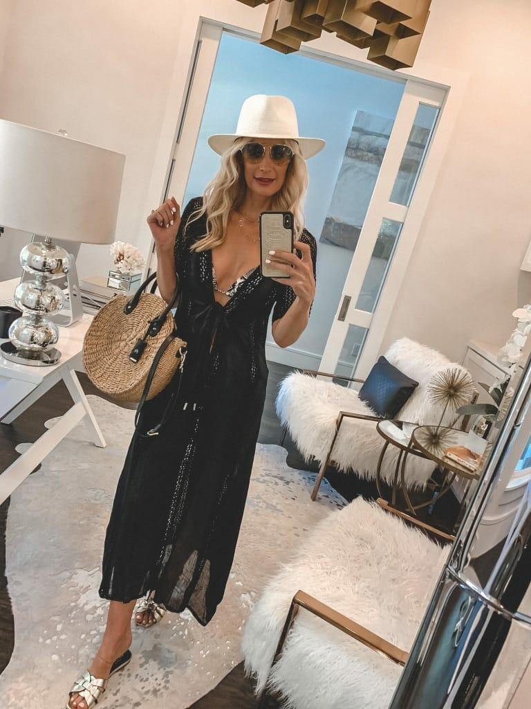 Style blogger wearing a black swimsuit cover-up and a summer hat
