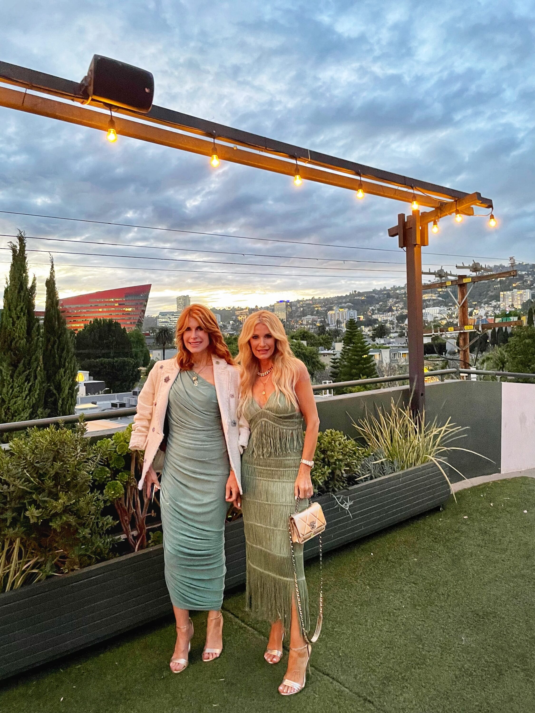 Dallas fashion bloggers over 40 wearing green fringe top and matching skirt with gold strappy heeled sandals and bag, an green ruched dress with ivory blazer and silver strappy heeled sandals