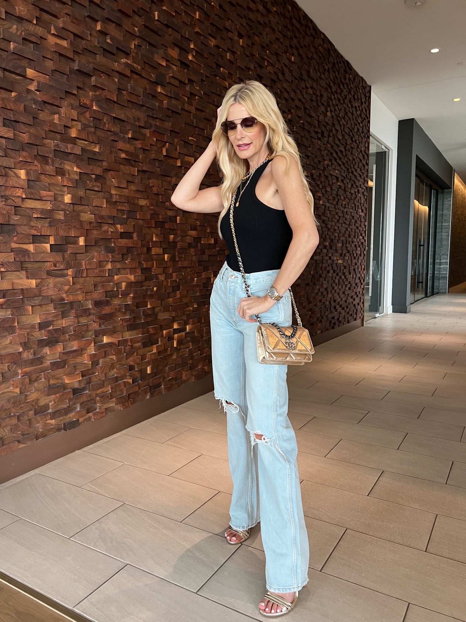 Dallas woman over 40 wearing distressed denim, black bodysuit and gold accessories 