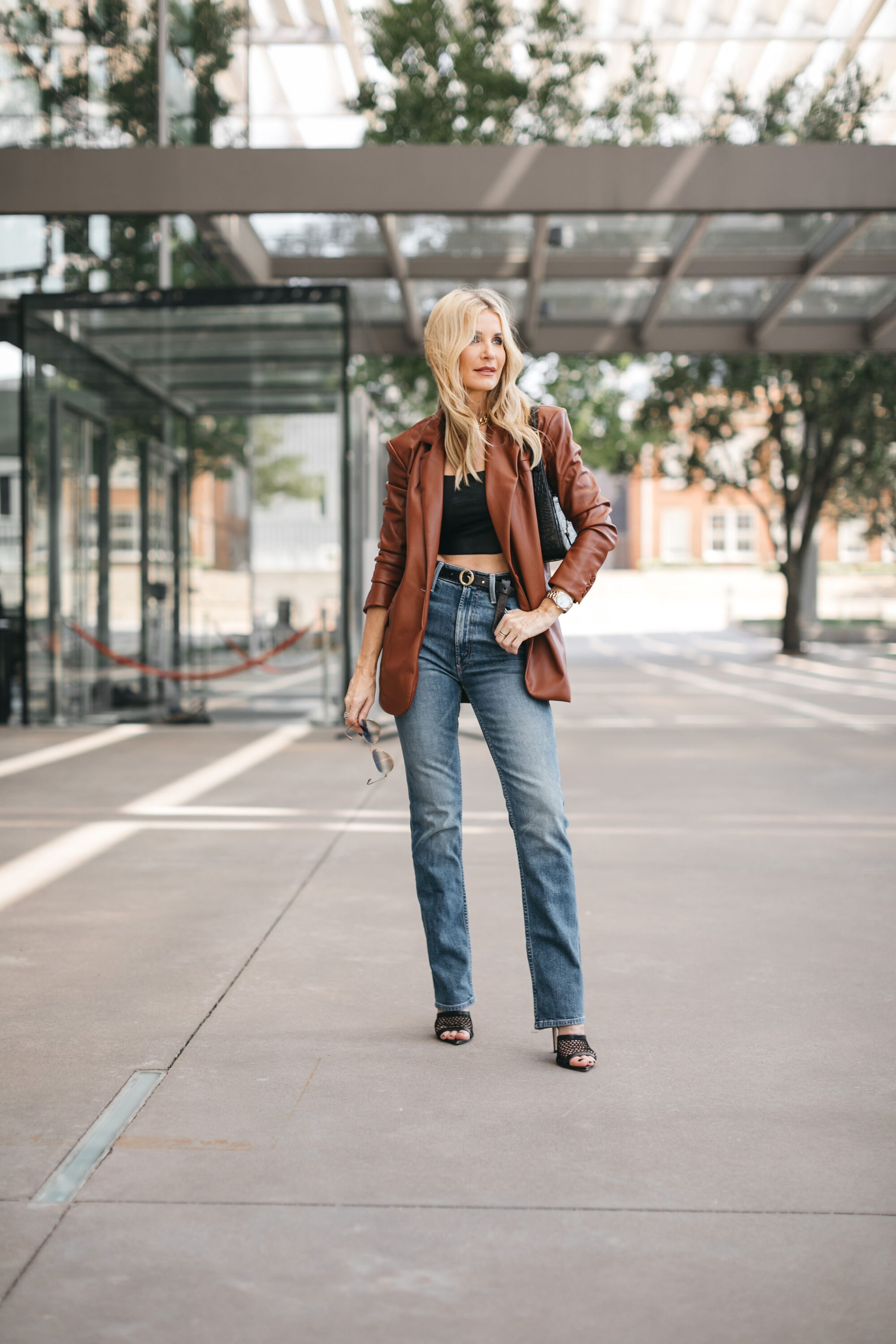 Over 40 fashion influencer wearing crop top and blazer with high waisted denim.