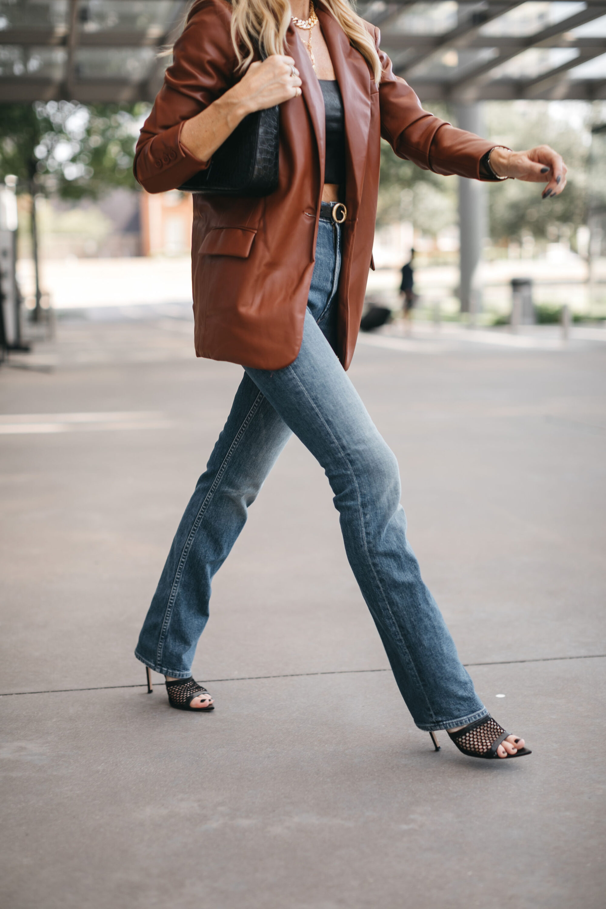 Over 40 fashion blogger wearing straight leg jeans with no distressing and faux leather blazer with crop top.