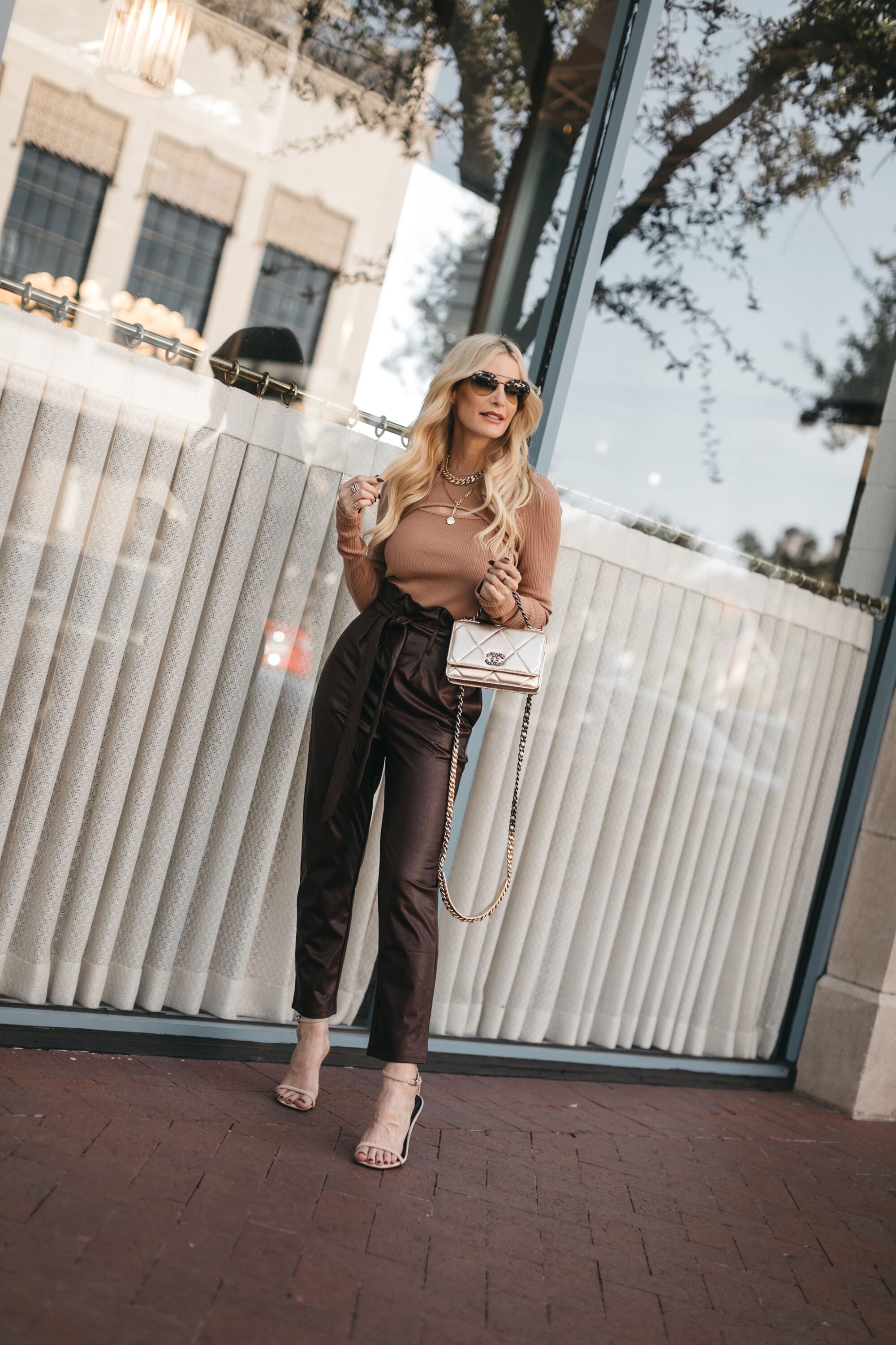 Over 40 Dallas fashion influencer wearing paper bag waist pants with cut out sweater and statement heels.