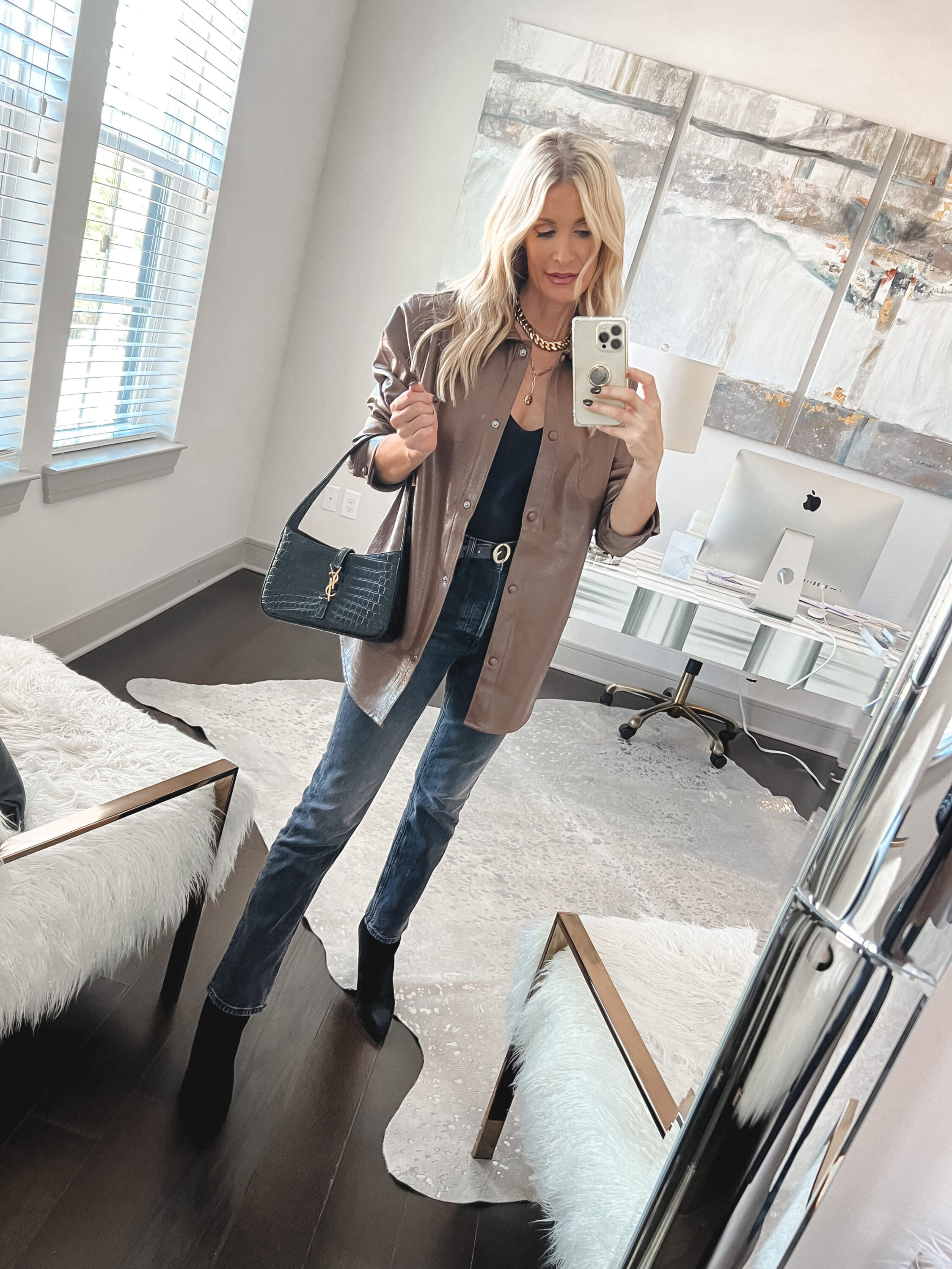 Woman over 40 wearing cropped jeans with a faux leather shacket and ankle booties.