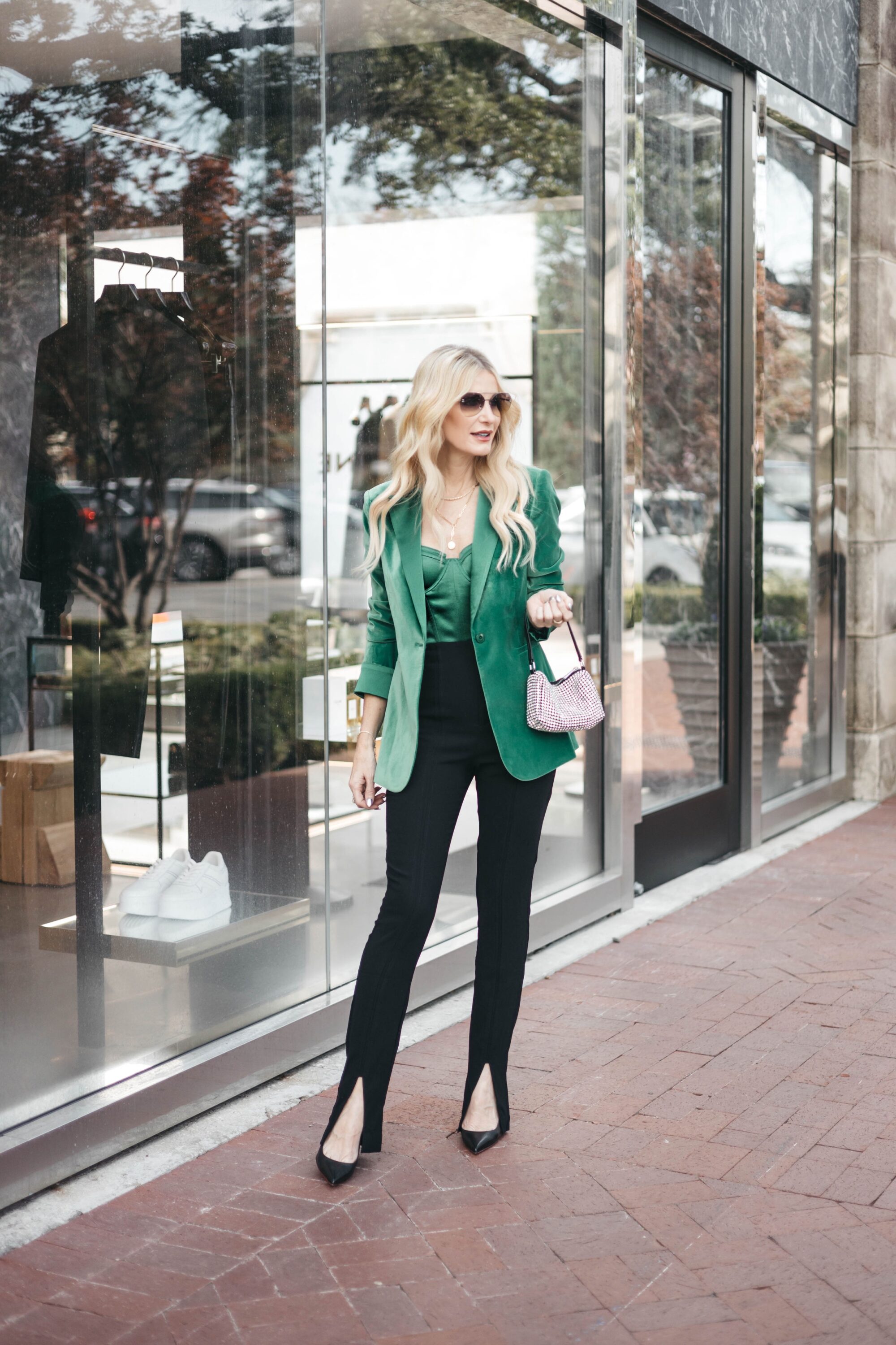 Over 40 fashion influencer wearing green bustier top with green velvet blazer and black faux leather pants as one of 5 holiday outfits for women over 40.