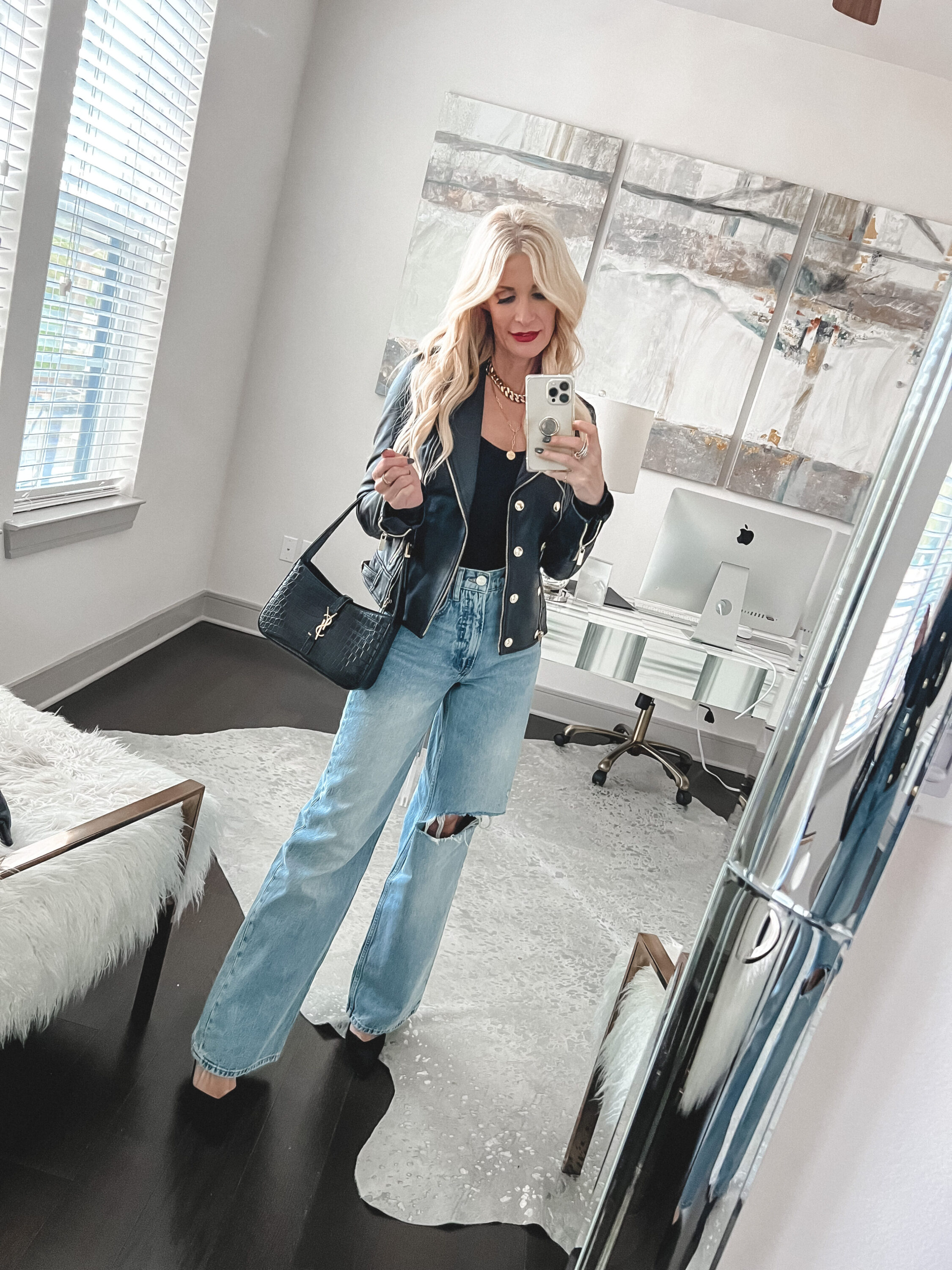 Over 40 fashion influencer wearing wide leg jeans and a black leather jacket.