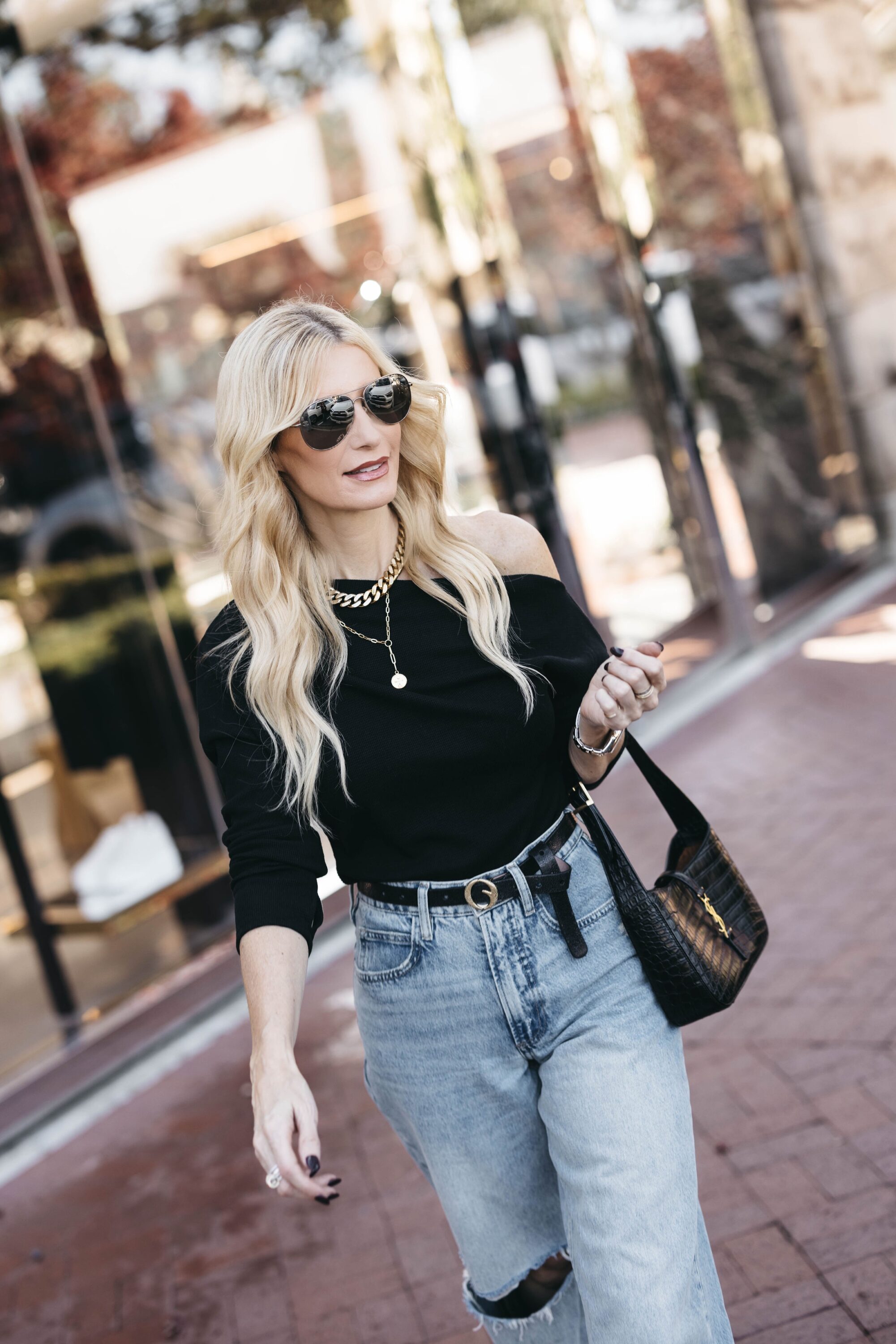Over 40 woman wearing baggy jeans with black off the shoulder top.