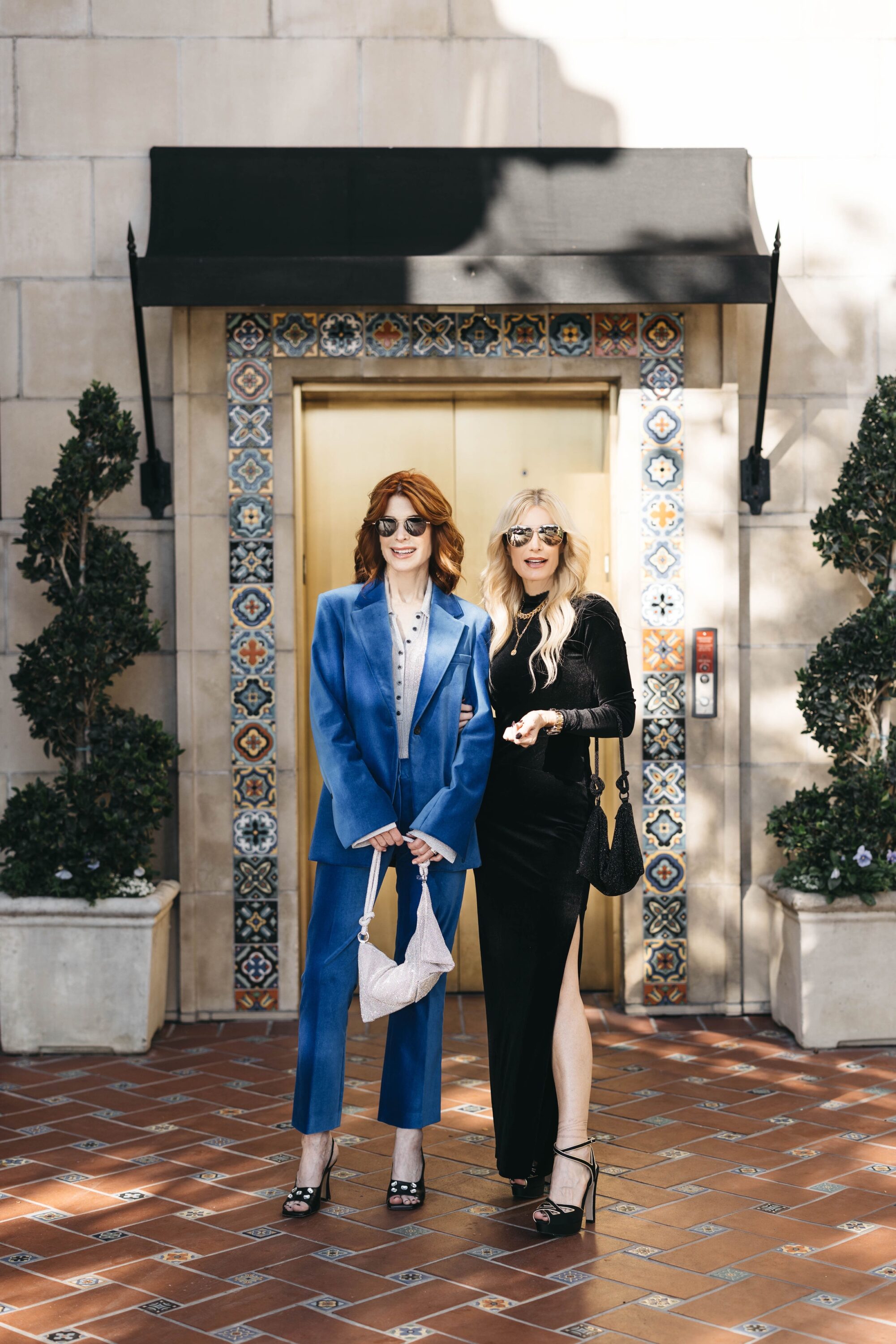 Women over 40 wearing black sweater dress with black platform sandals and rhinestone bag and blue blazer and matching pants.
