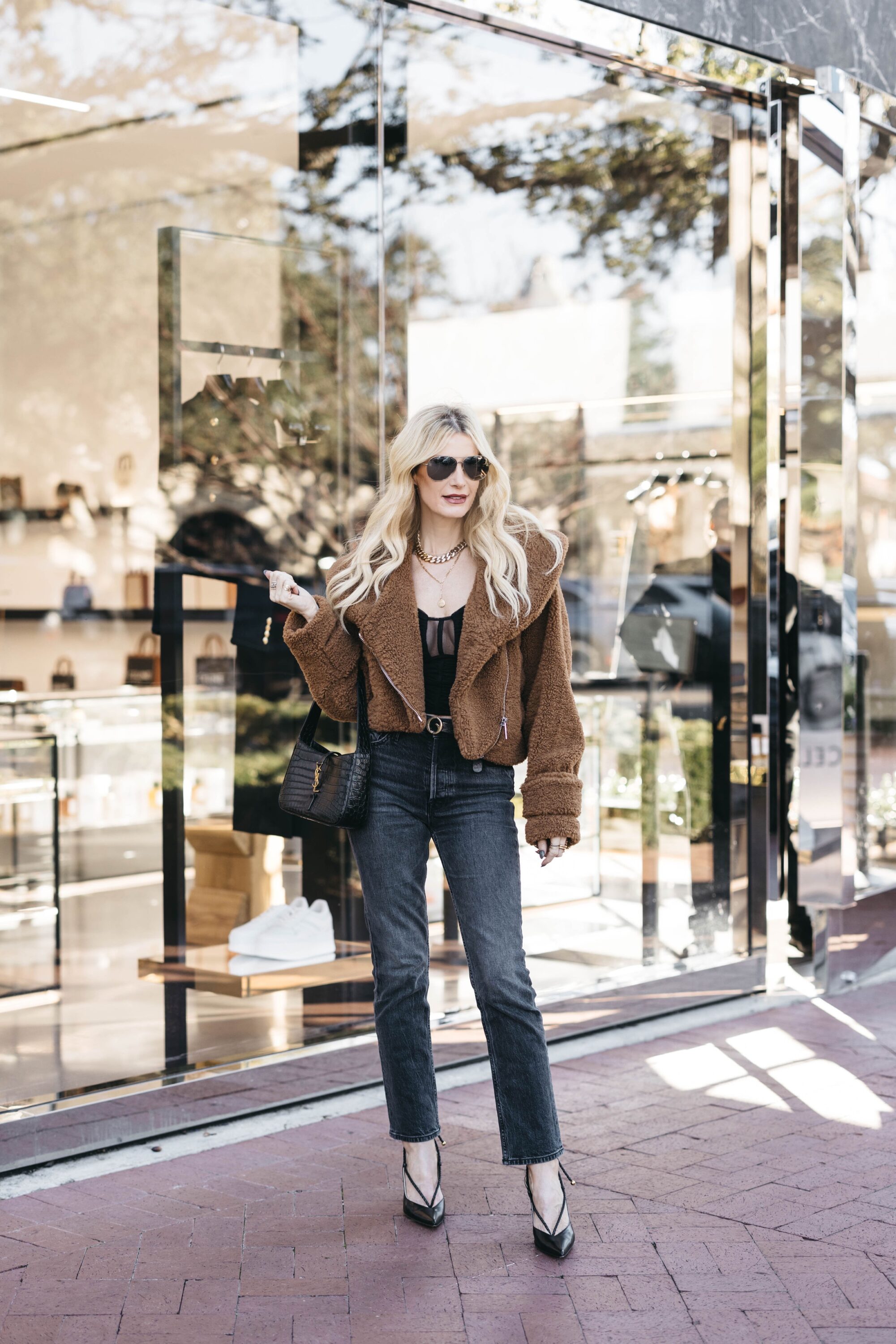 Over 40 woman wearing brown teddy jacket with black denim and black mesh bodysuit as one of 5 ways to wear a faux fur jacket.