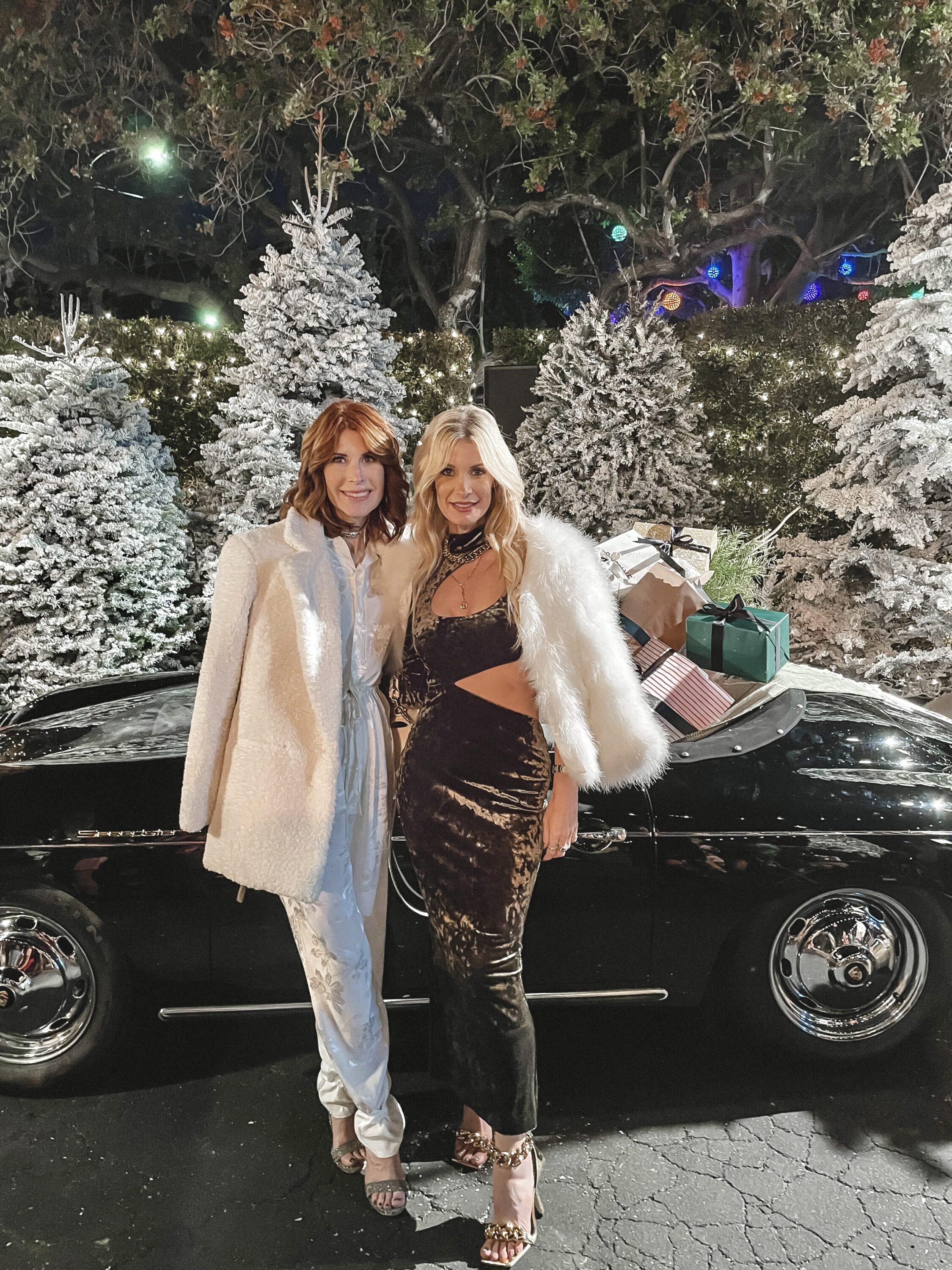 Fashion influencers over 40 wearing white jumpsit and velvet cut out dress with white faux fur coats as an example of what to wear on New Year's Eve 2023.