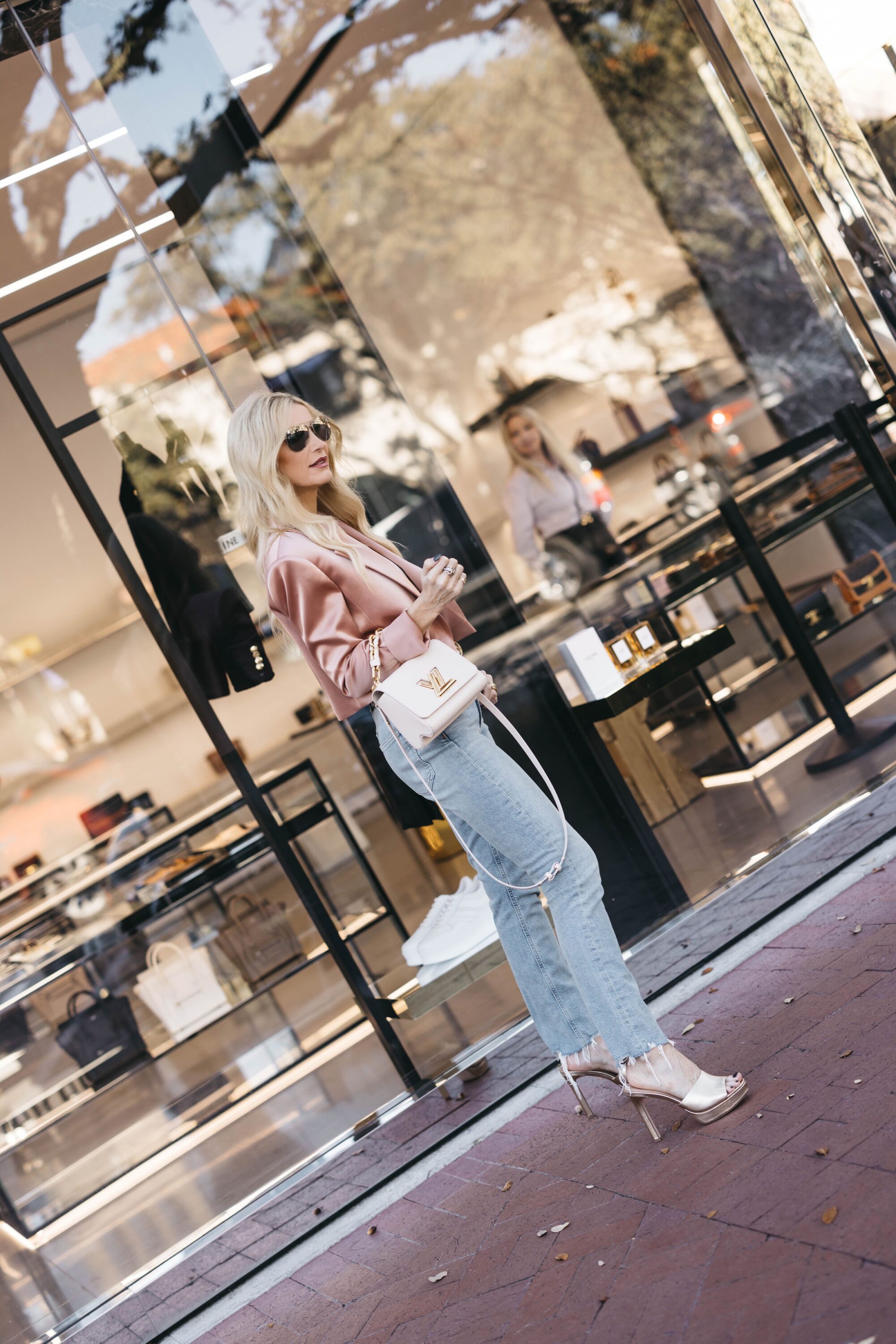 Over 40 fashion influencer wearing platform sandals with straight leg high-waisted jeans and a satin blazer.