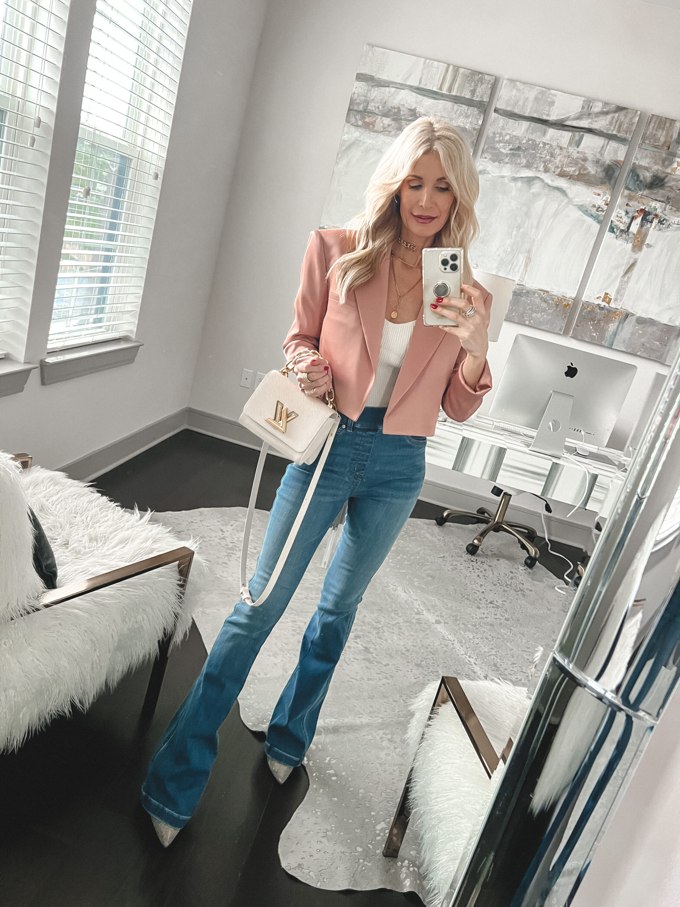 woman over 40 stlying the best denim for women over 40 with a pink satin blazer white bodysuit and rhinestone heels.