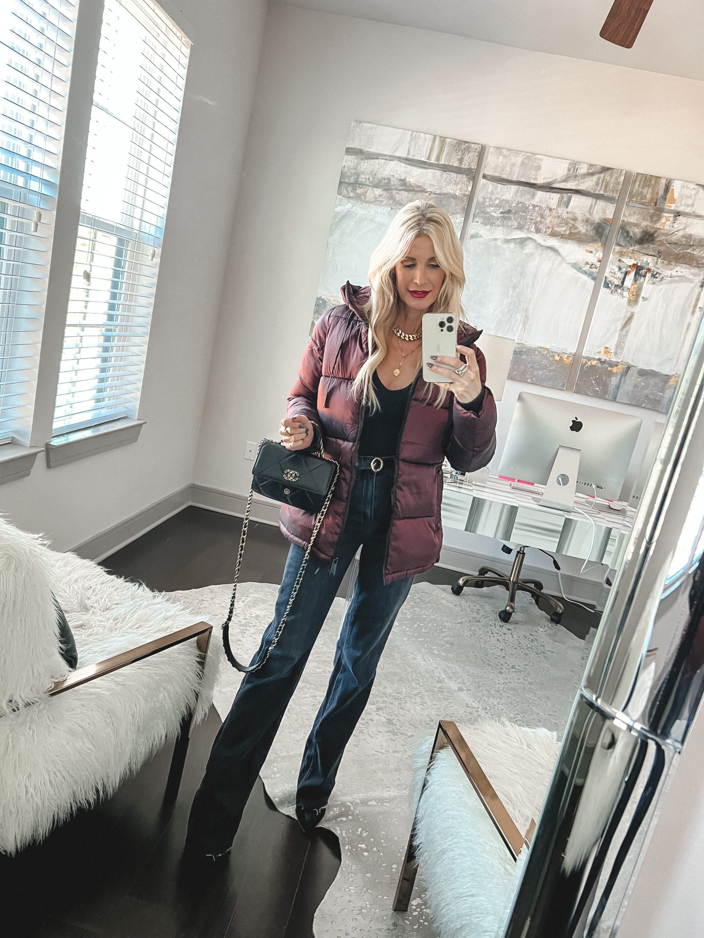 Woman over 40 wearing best selling burgundy puffer jacket on sale with black vintage wash jeans and black bodysuit.