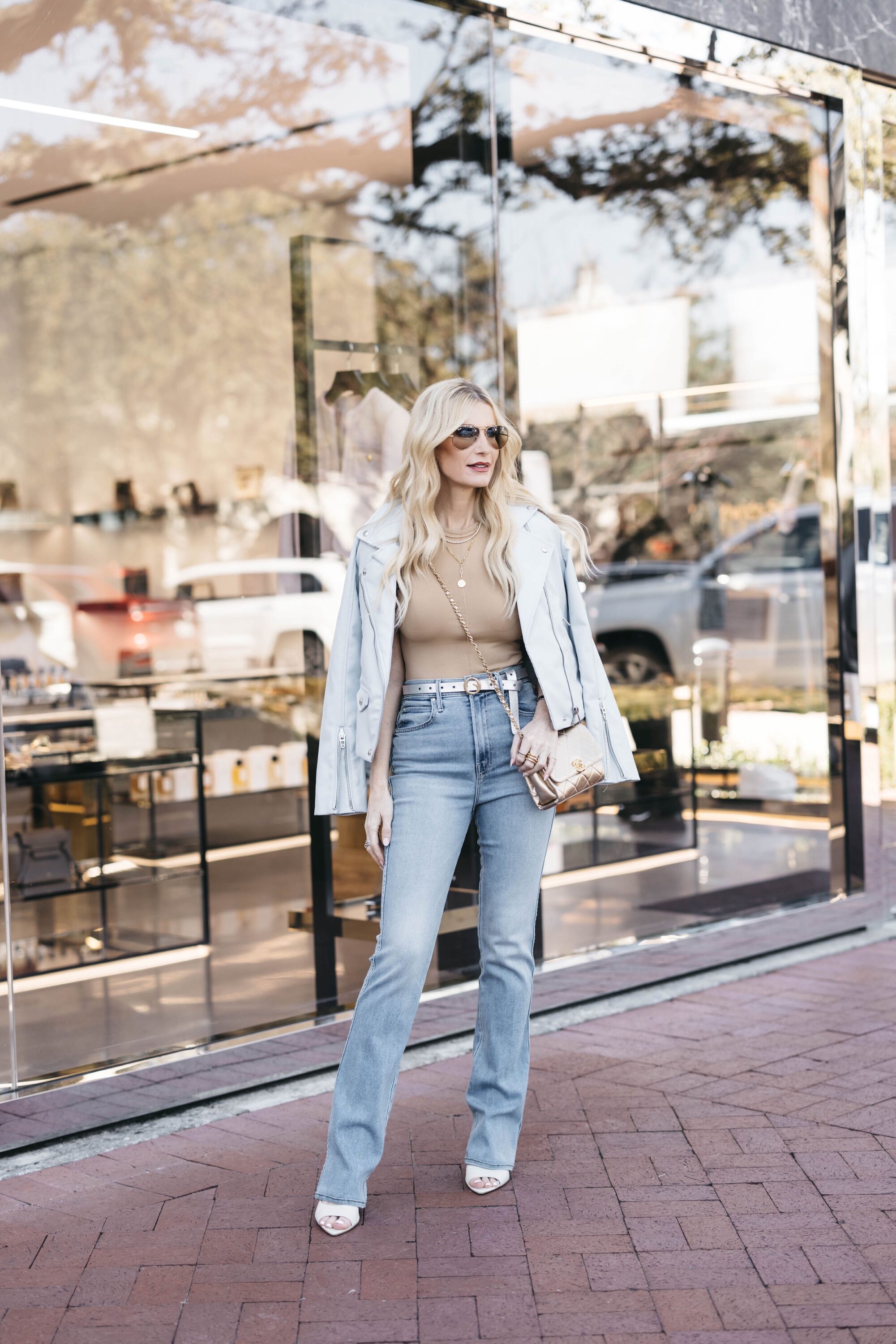 Over 40 fashion blogger wearing a blue motor jacket with mother jeans and brown bodysuit as one of 5 spring must-haves