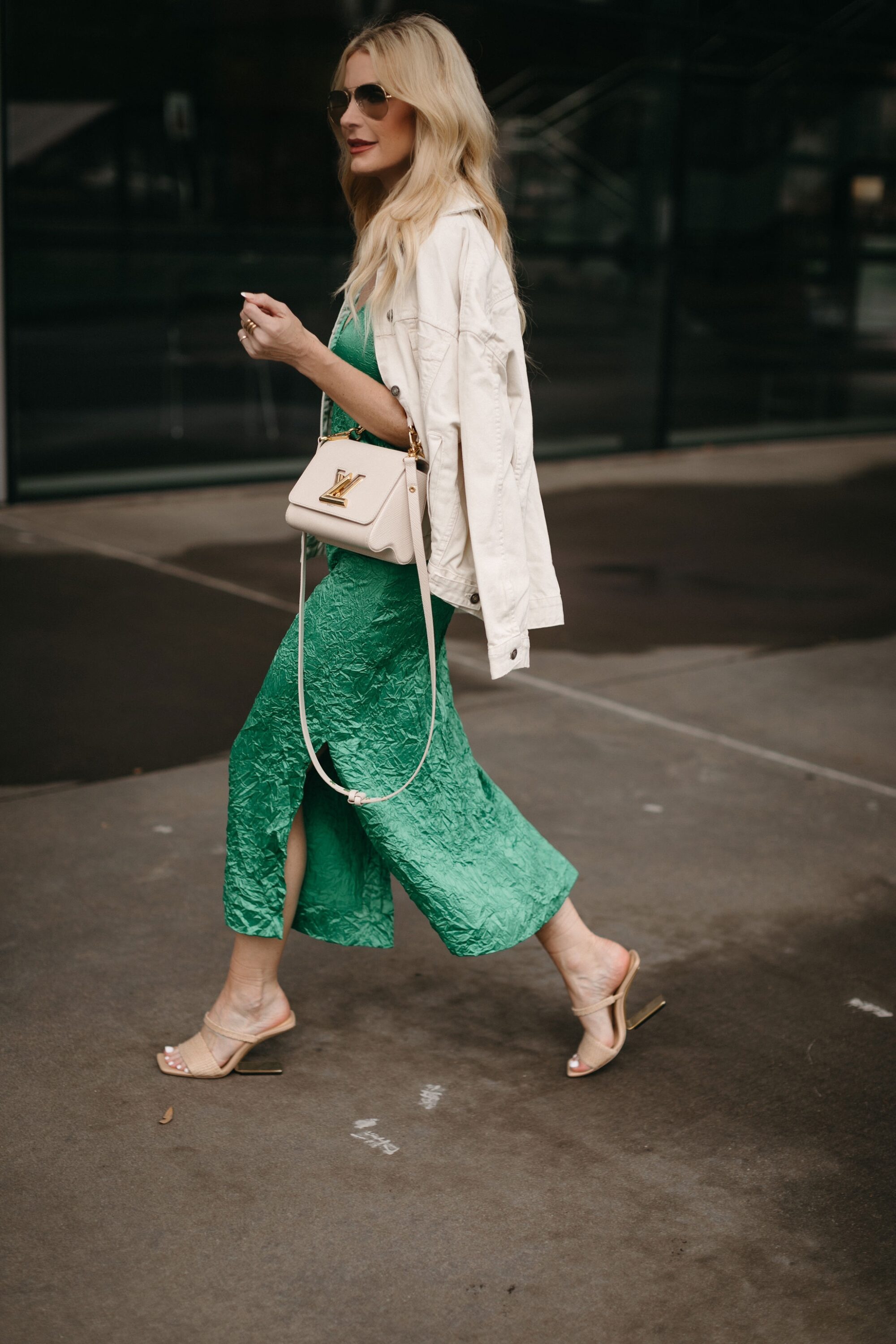 Ivory Denim jacket draped over shoulders of over 40 fashion influencer from Dallas while wearing green crinkled satin dress.