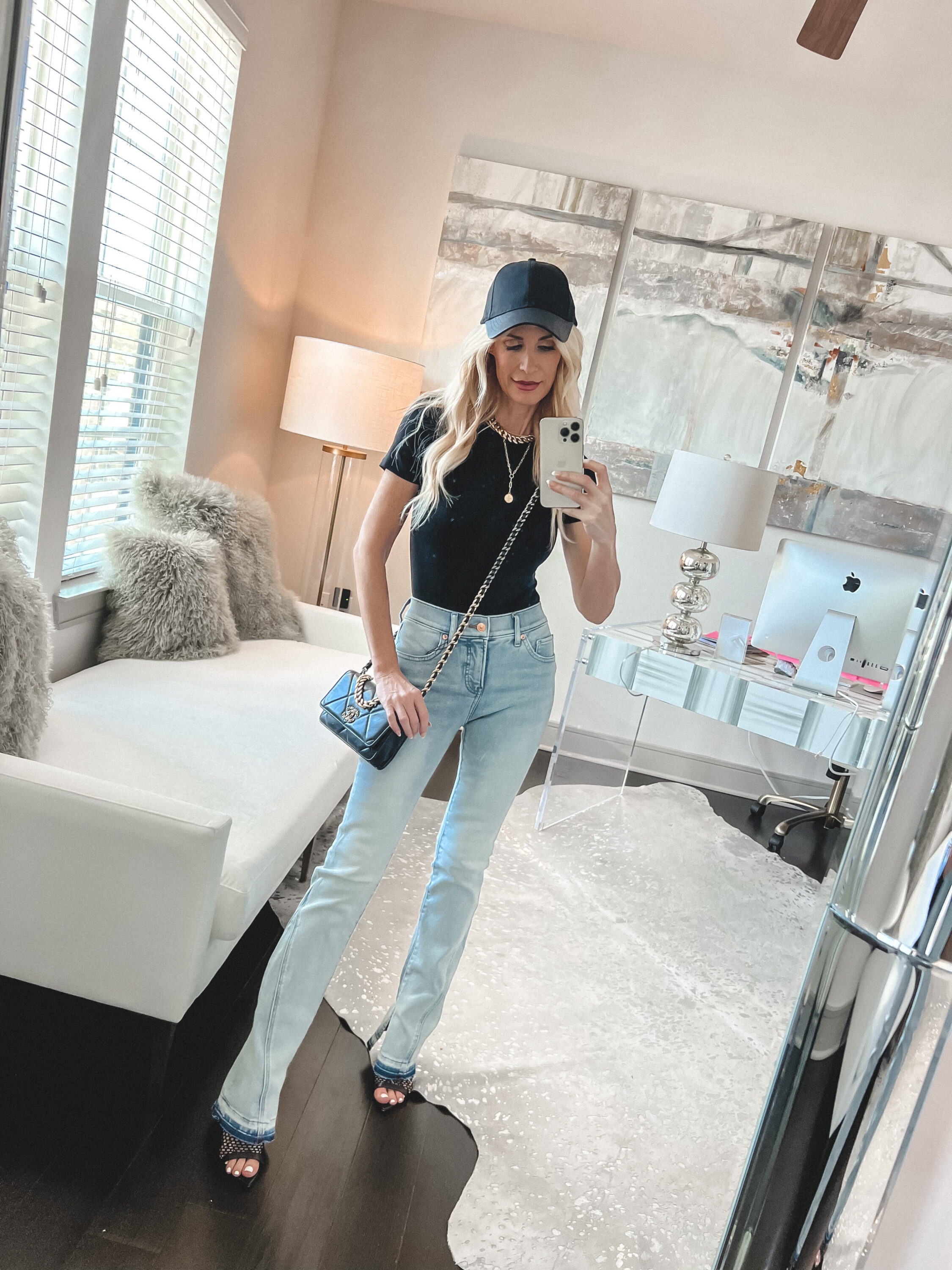 Over 40 fashion influencer from Dallas wearing light wash jeans from Express with a black tee and black hat.