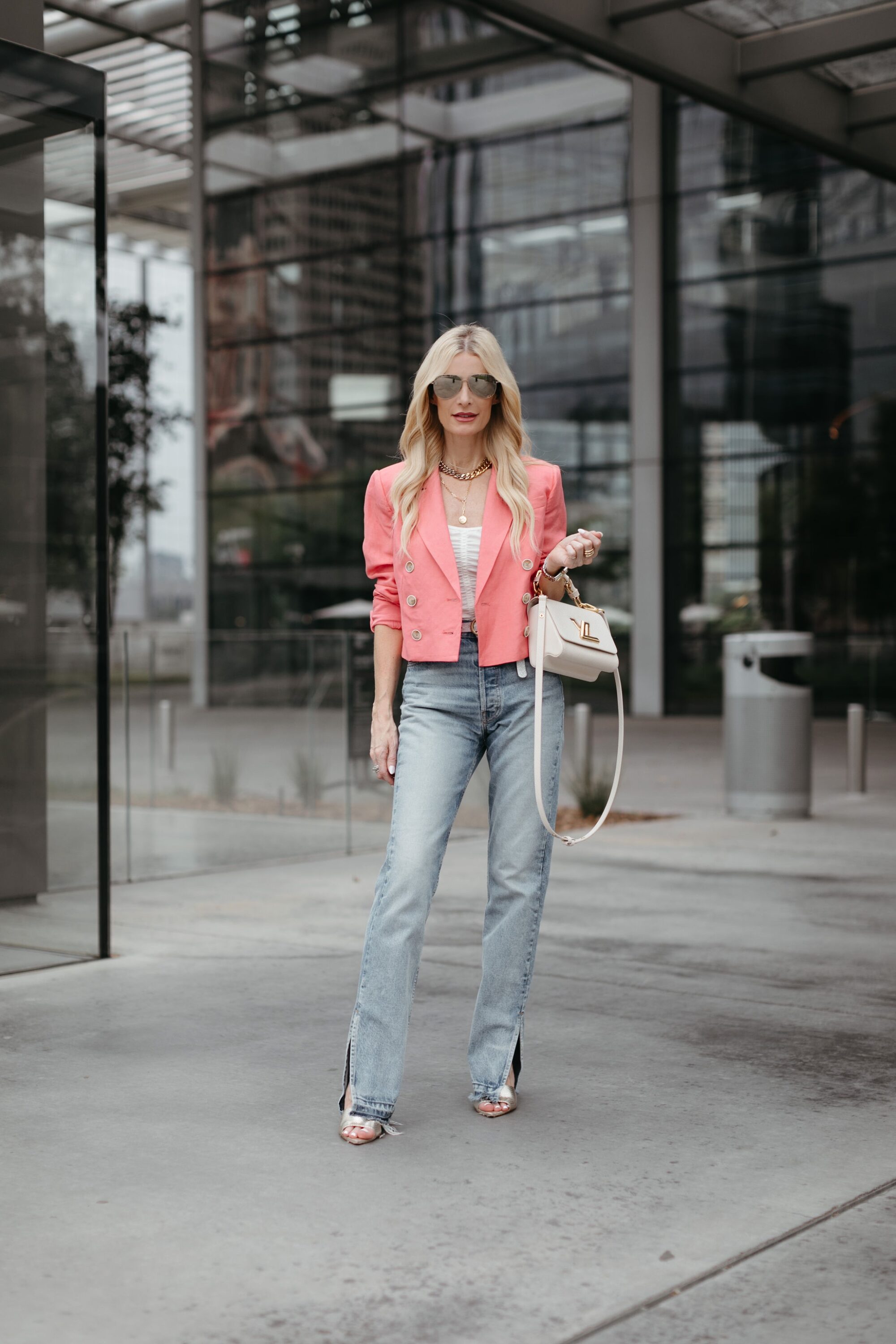Over 40 Dallas fashion influencer wears a pink blazer over a white tank bodysuit paired with a set of EB denim as one of the most flattering denim for women over 40.