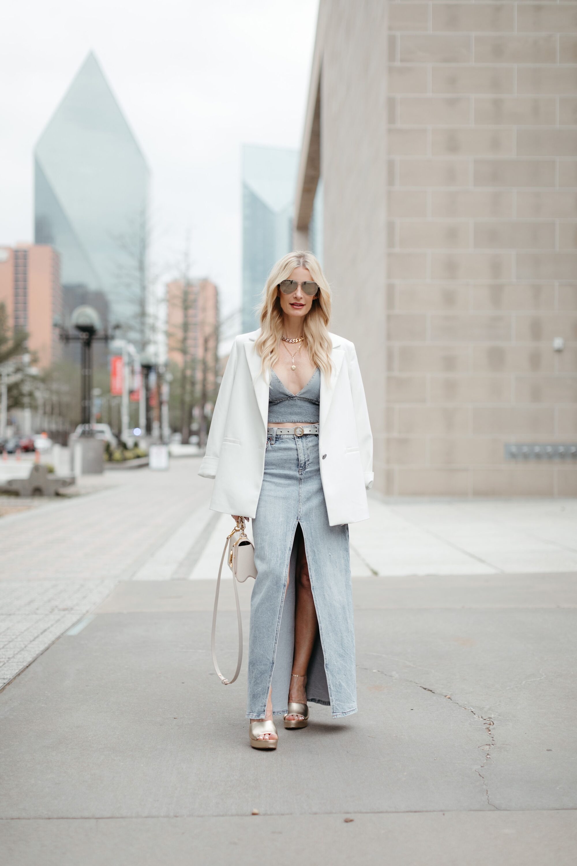 Dallas fashion influencer wears a denim maxi skirt with a denim bra top and a leather blazer over top as her 3rd layer to create balance.