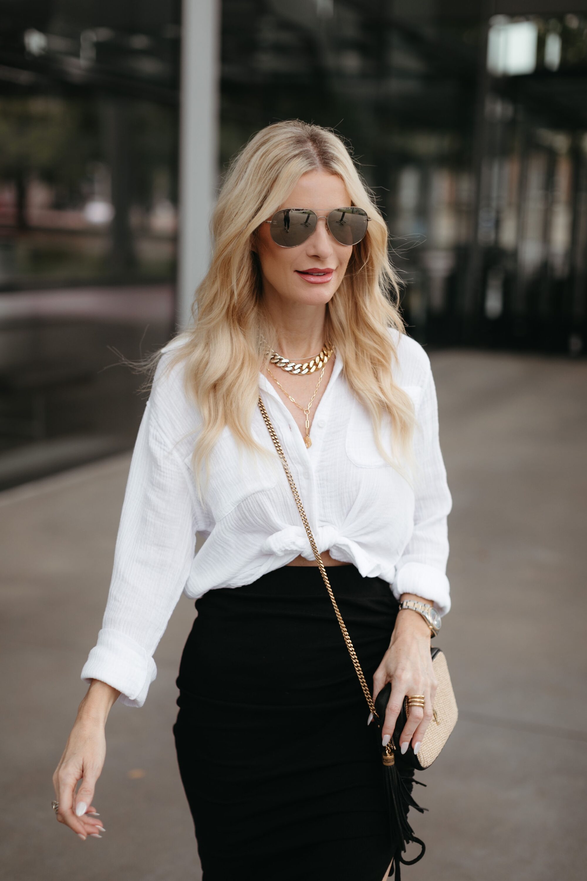 A black skirt and a white gauzy button-down shirt is worn by a over 40 fashion blogger on the streets of Dallas.