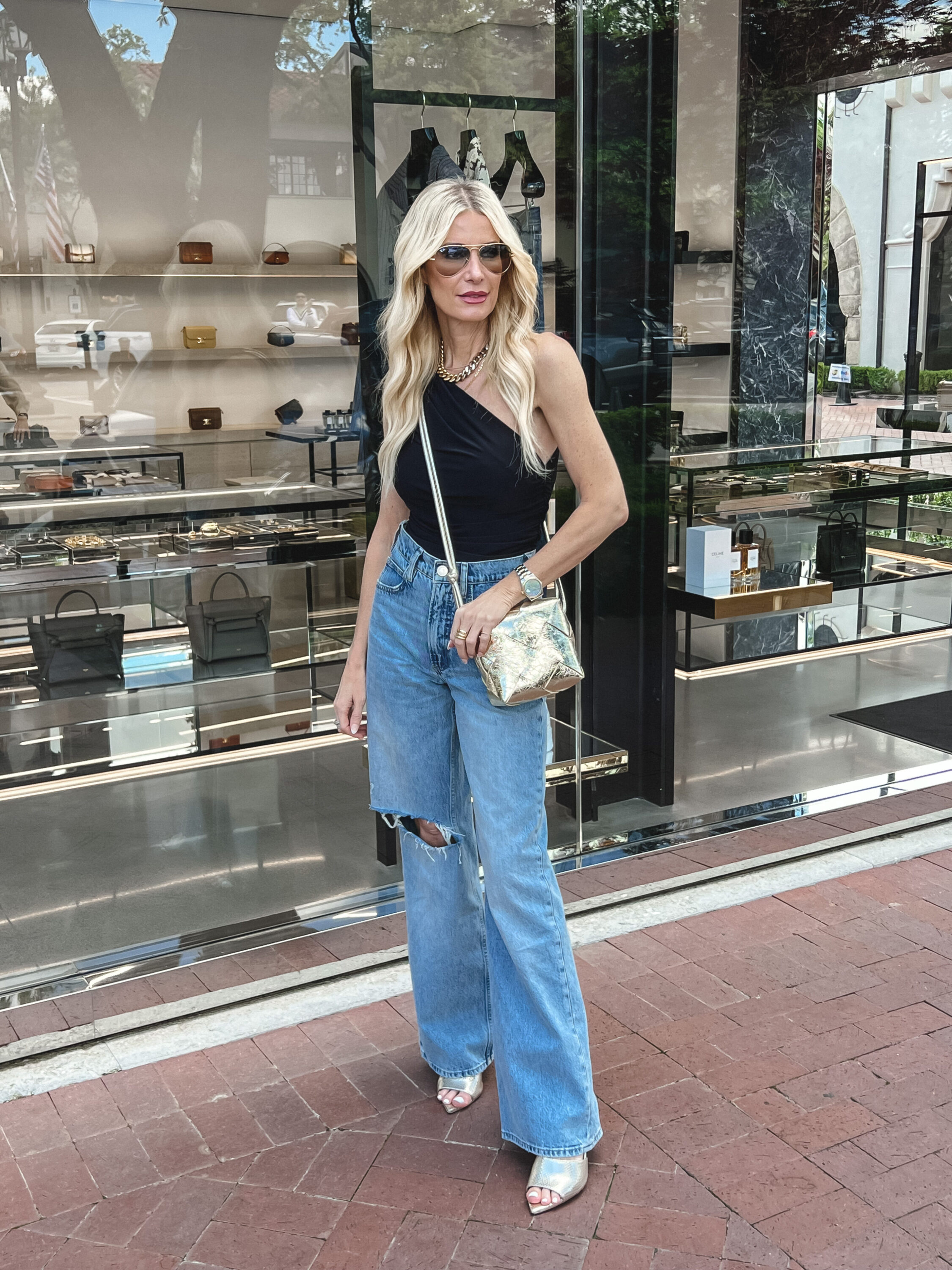 Fashion influencer for the Over 40 crowd wearing wide-leg jeans with a black one-shoulder top.