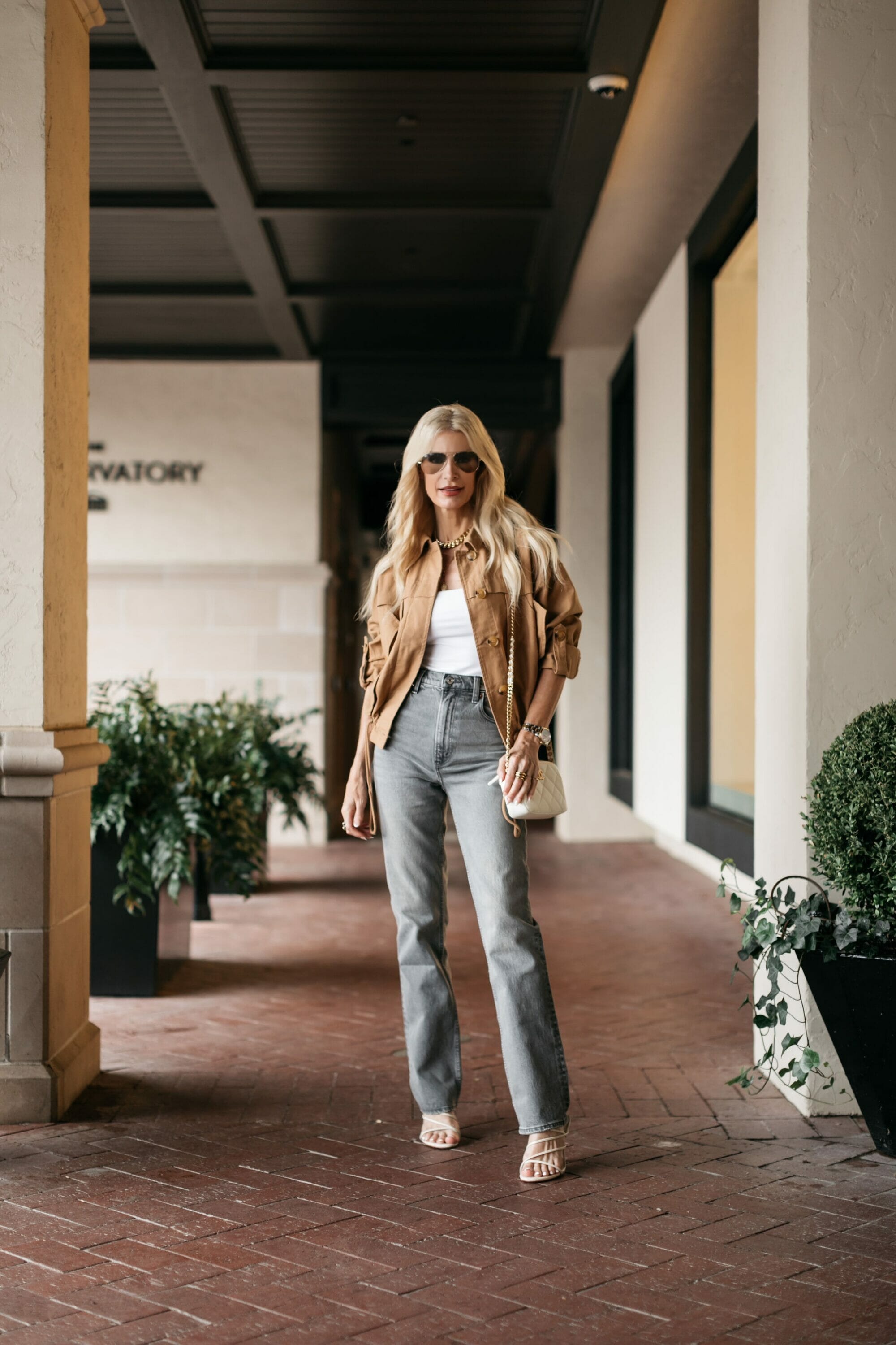 Over 40 fashion stylist showcasing light summer jackets and a white bodysuit and straight leg jeans.