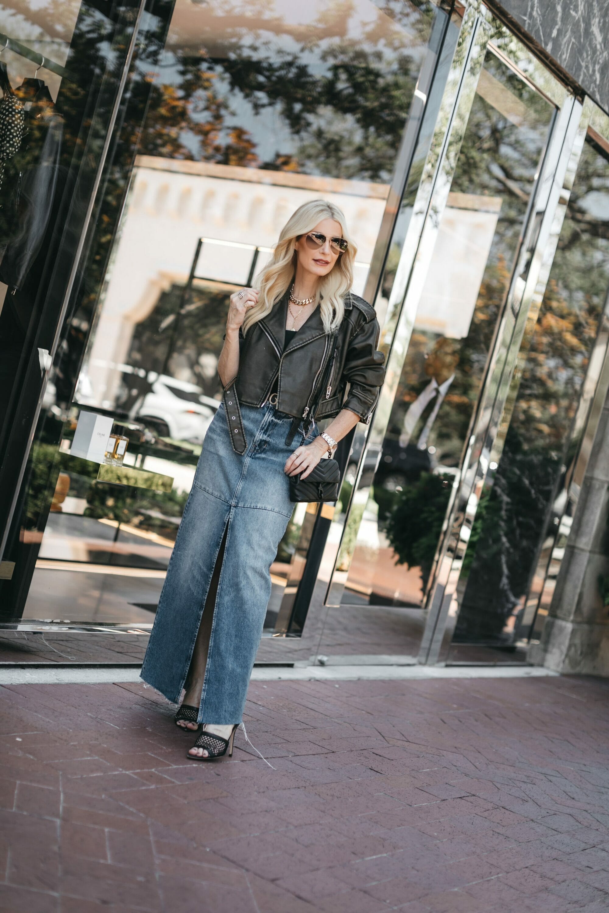 Dallas fashion influencer over 40 wearing denim midi skirt with cropped leather jacket as examples of key fall pieces your wardrobe needs.
