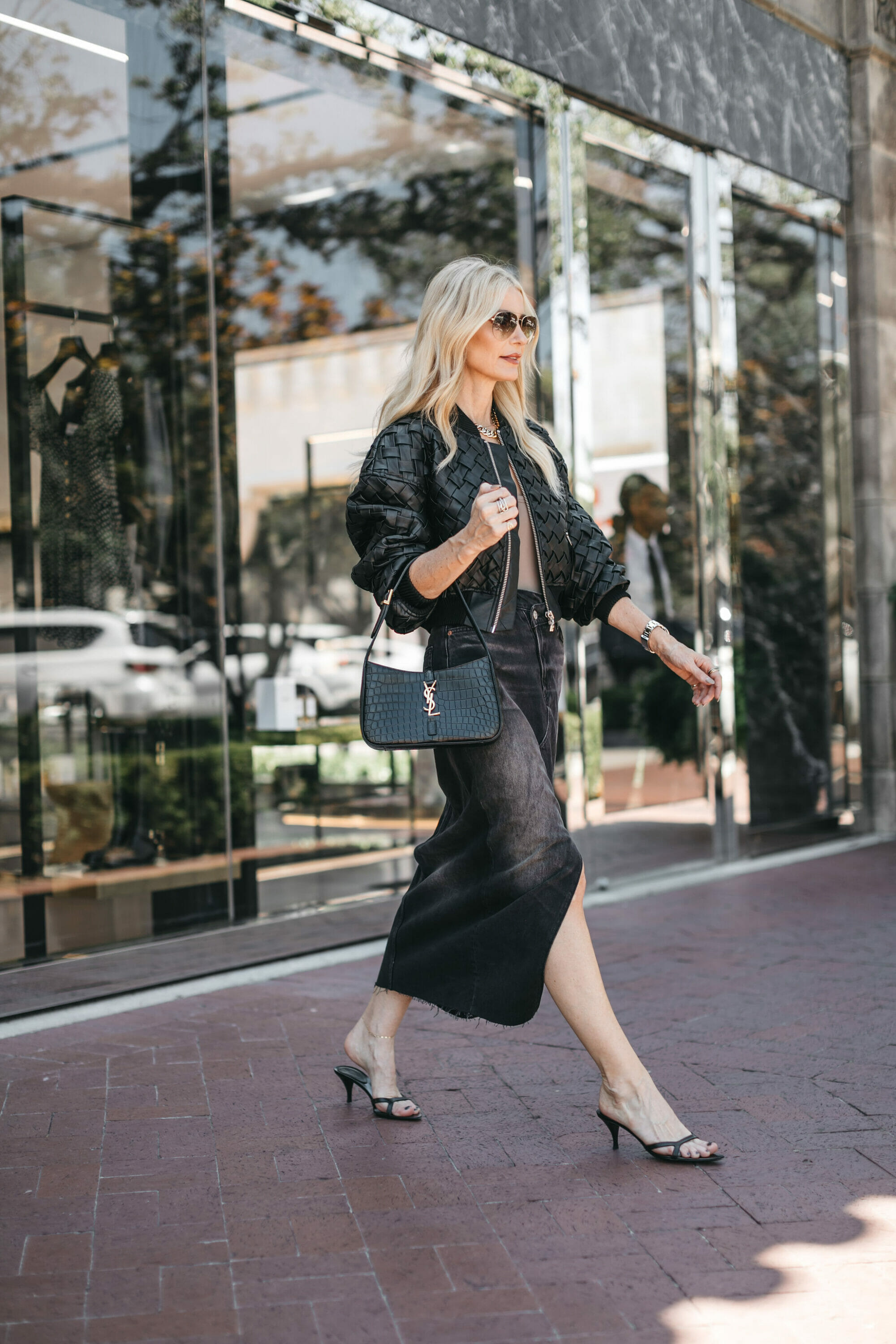 Dallas fashion influencer for over 40 niche wearing a black quilted leather jacket with a black denim midi skirt as one of 5 examples of how to style a denim midi skirt.