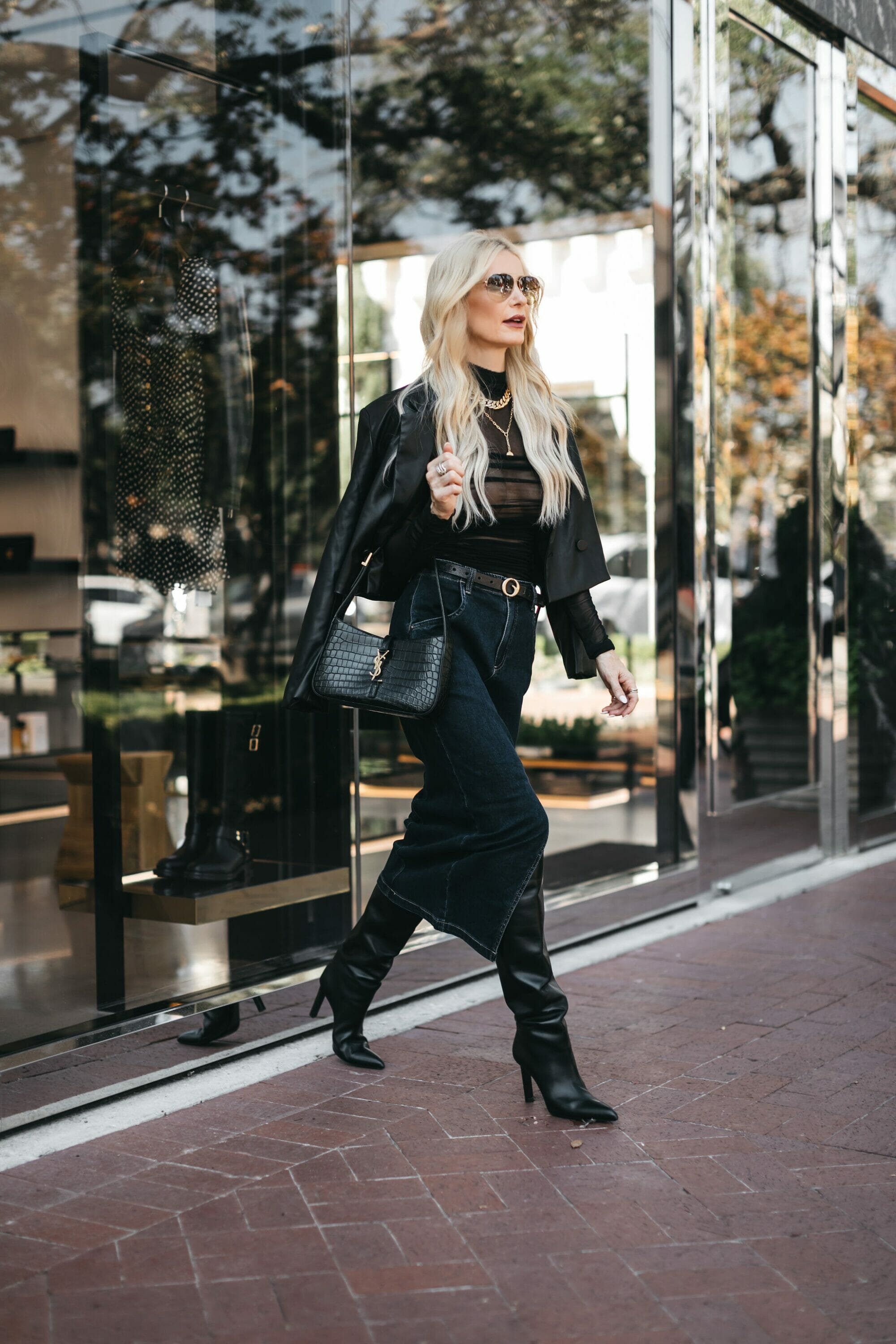 Over 40 fashion blogger wearing sheer bodysuit with knee-high boots and a denim maxi skirt as some of the most wearable fall fashion trends.