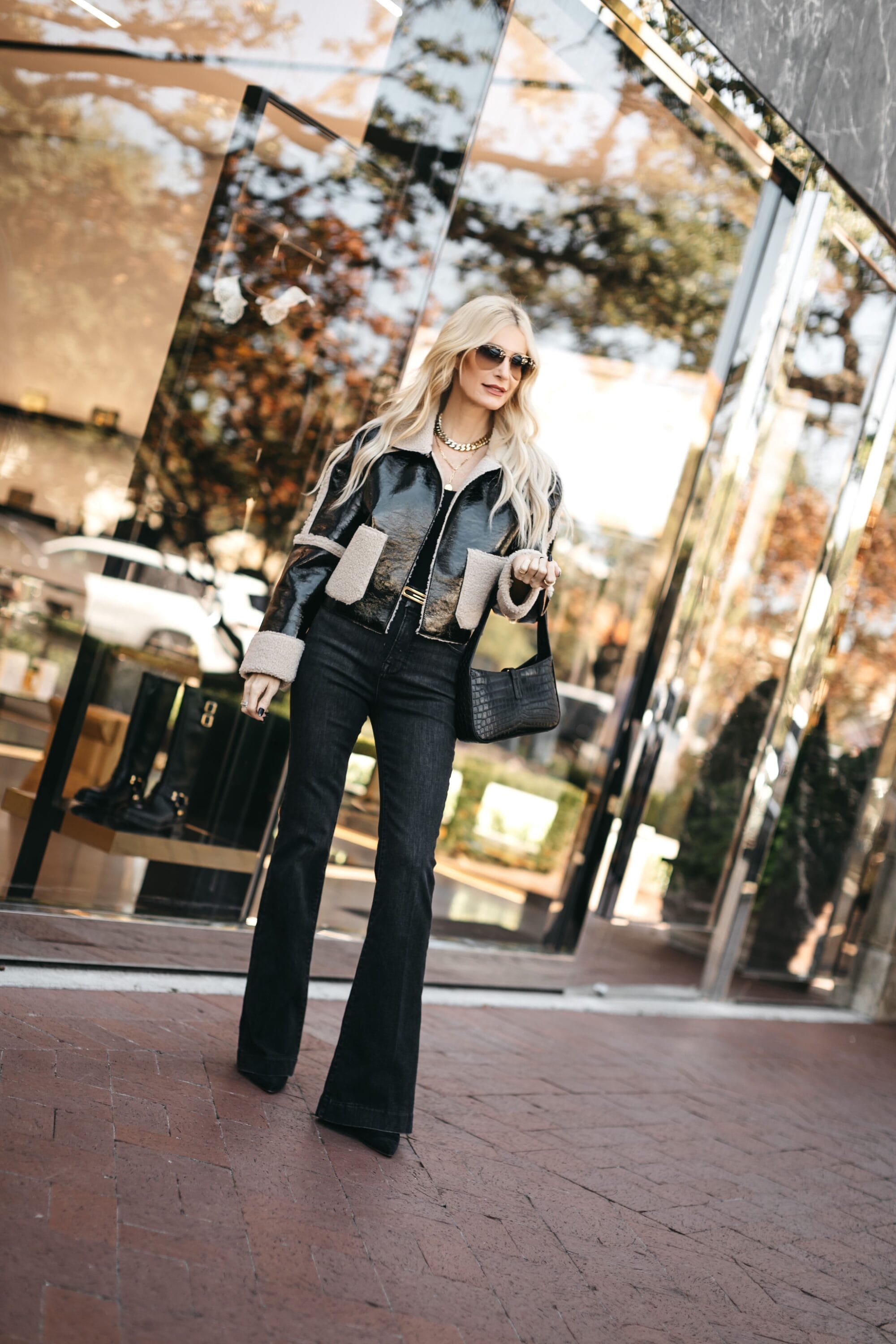 Over 40 fashion influencer wearing a Steve Madden faux fur trimmed jacket with black flare jeans and slingback heels.