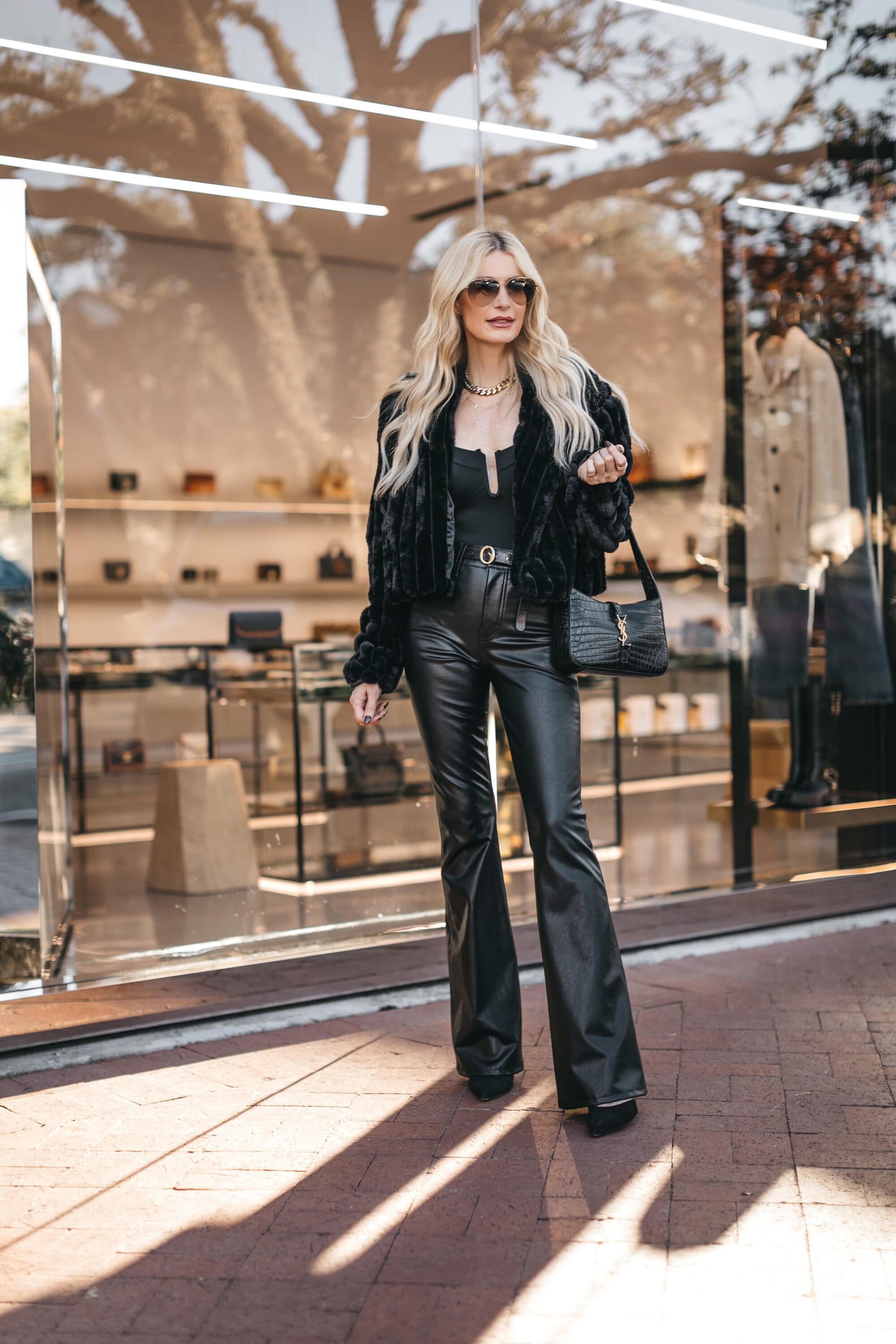 Dallas fashion influencer for women over 50 wearing a black faux fur coat with faux leather flares as an example of what to wear on New Year's Eve.