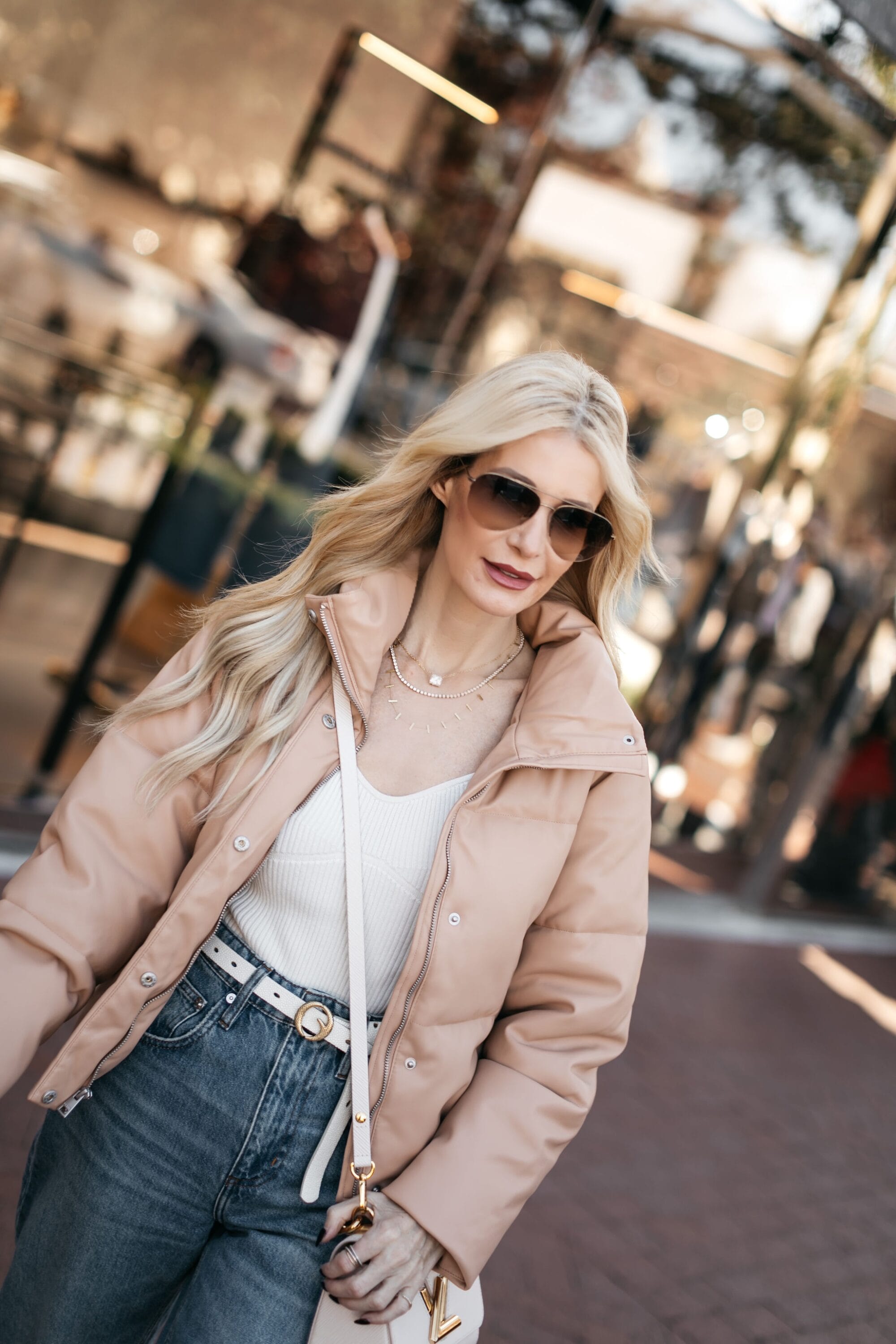 Over 40 fashion influencer wearing a faux leather puffer jacket with dark wash barrel jeans.