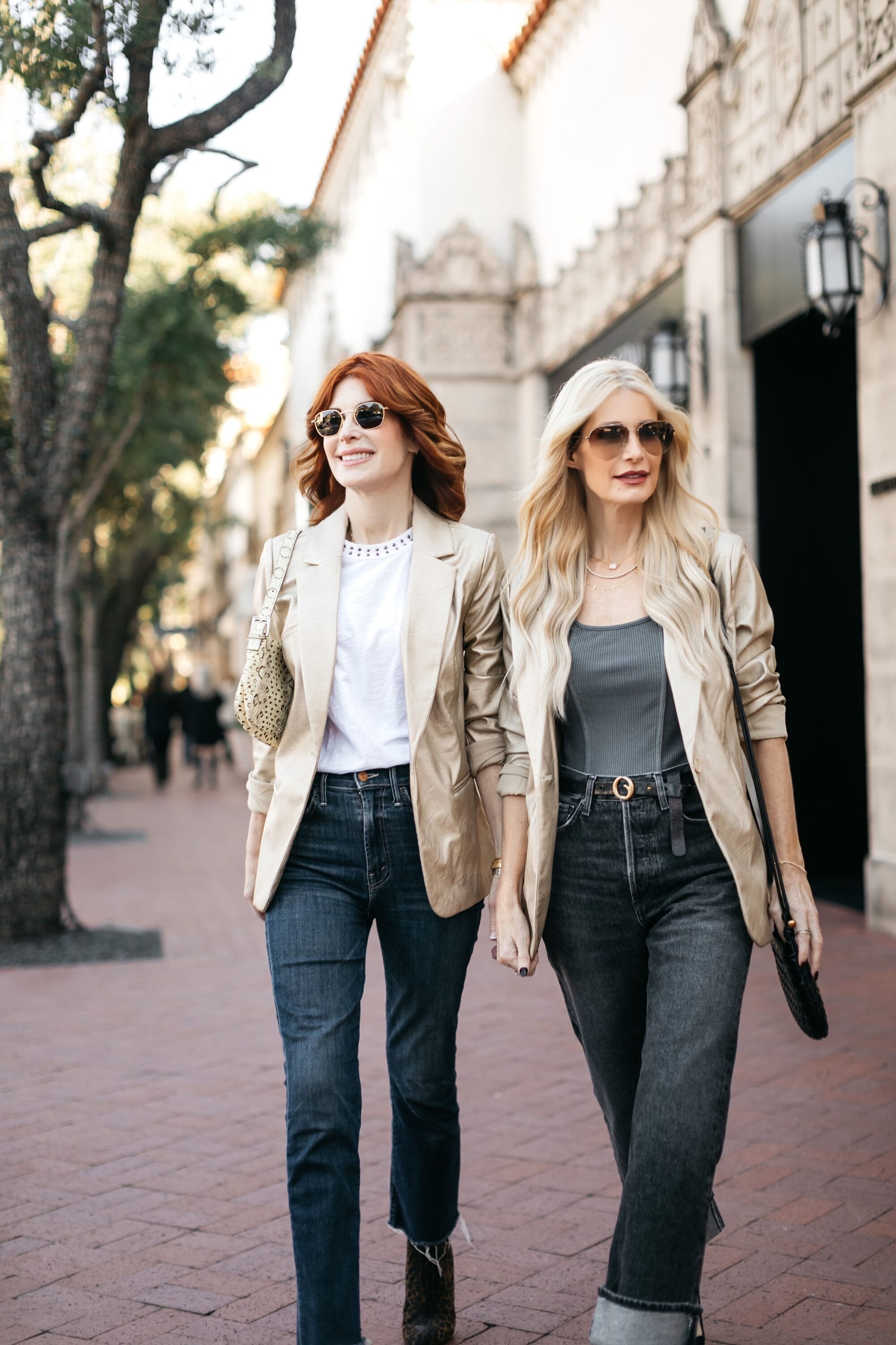 Dallas women over 40 walk down the street showcasing a gold blazer with dark grey cuffed denim and straight leg blue jeans.