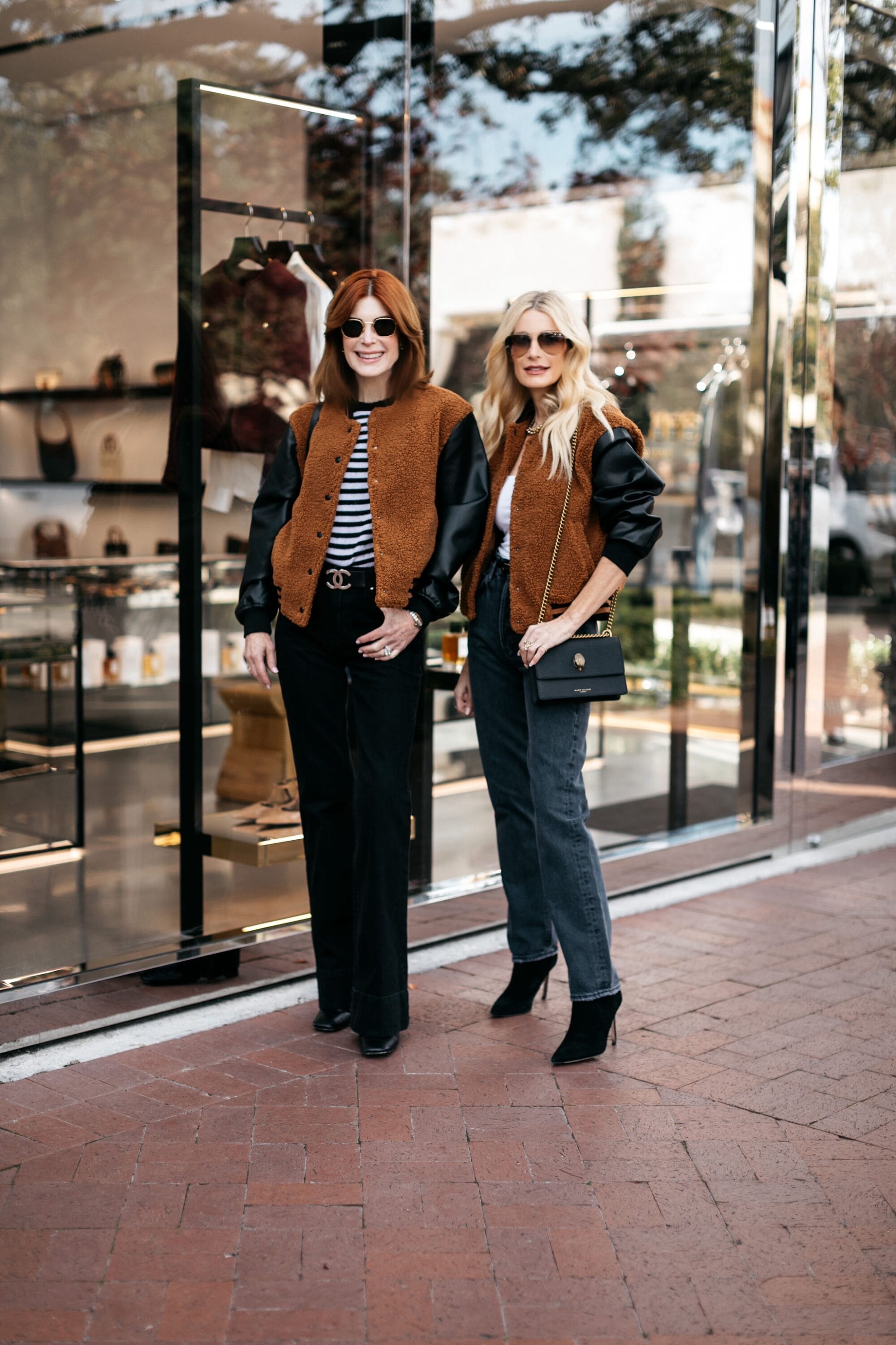 Dallas women over 40 wearing a camel and black shearling bomber jacket with black & faded black jeans.