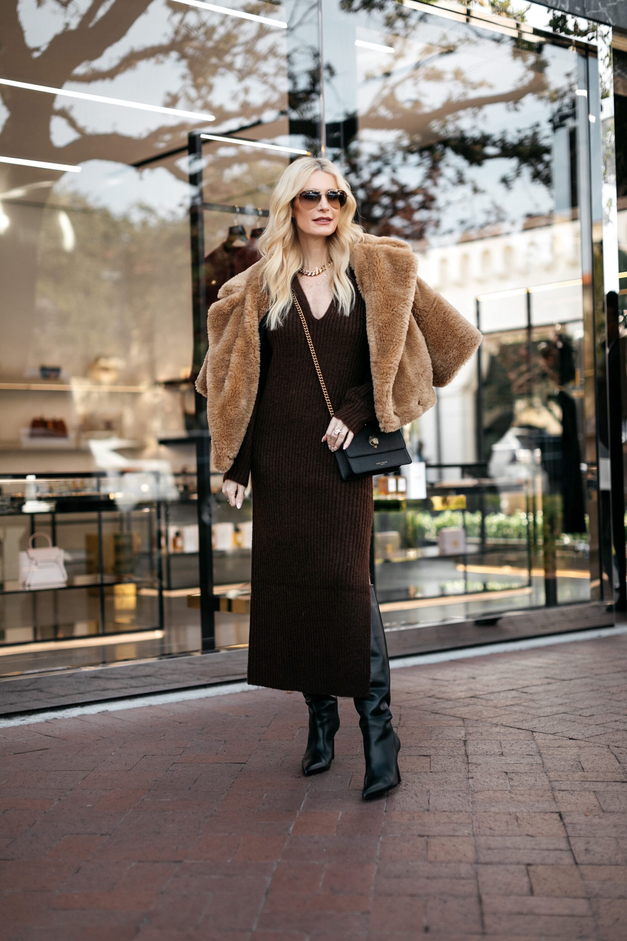 Dallas woman over 40 wears a brown maxi dress and black knee high boots.