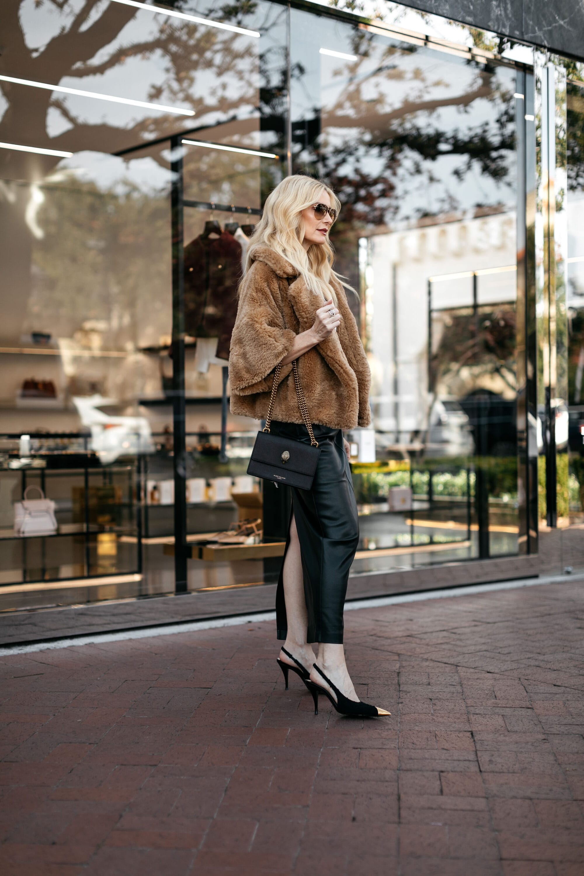Dallas fashion blogger for women over 40 wearing a black faux leather skirt with a oversized faux leather skirt and black & gold trimmed heels.