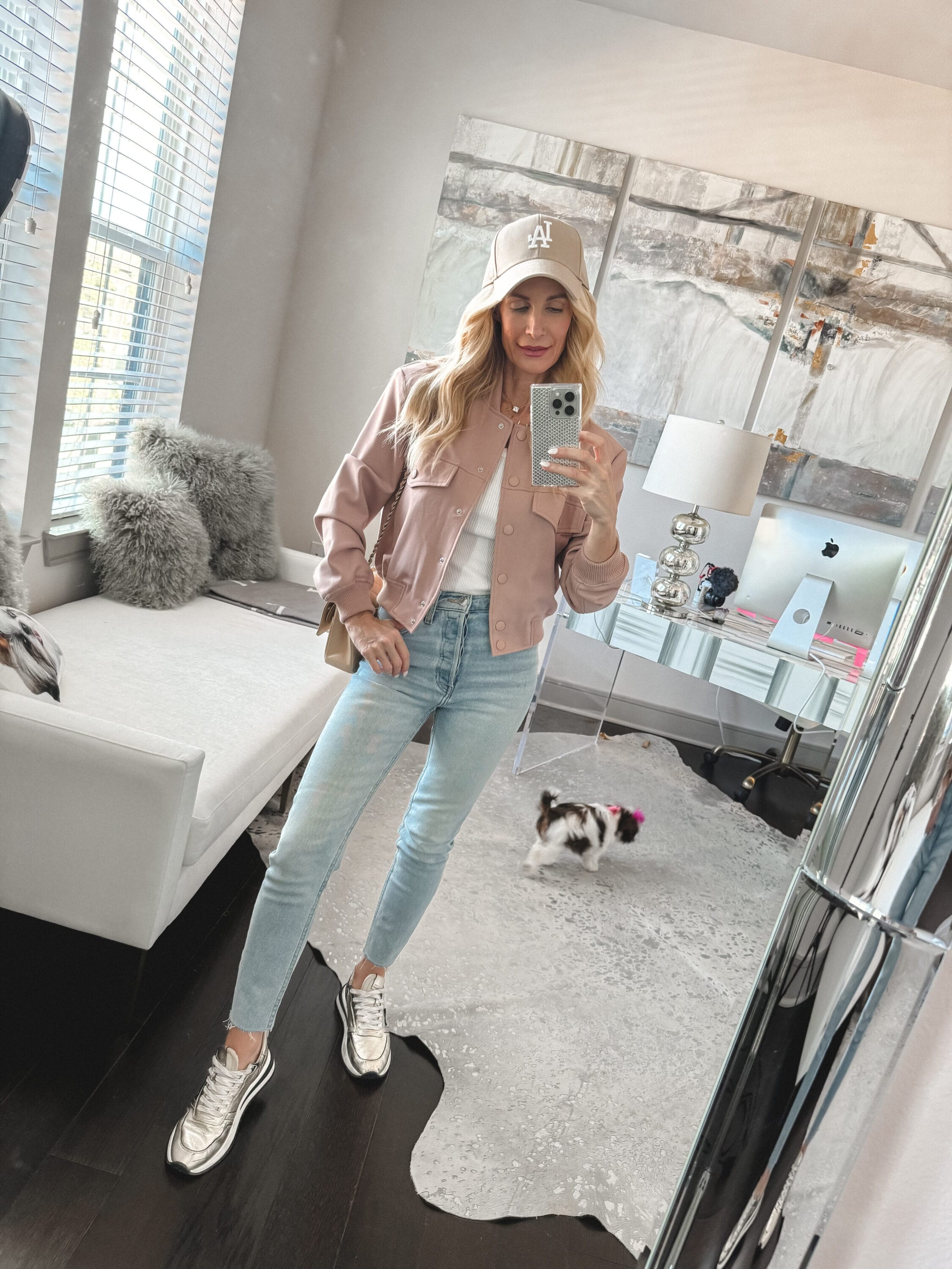 Dallas fashion blogger for women over 40 wearing straight leg jeans with a blush bomber jacker and gold sneakers.