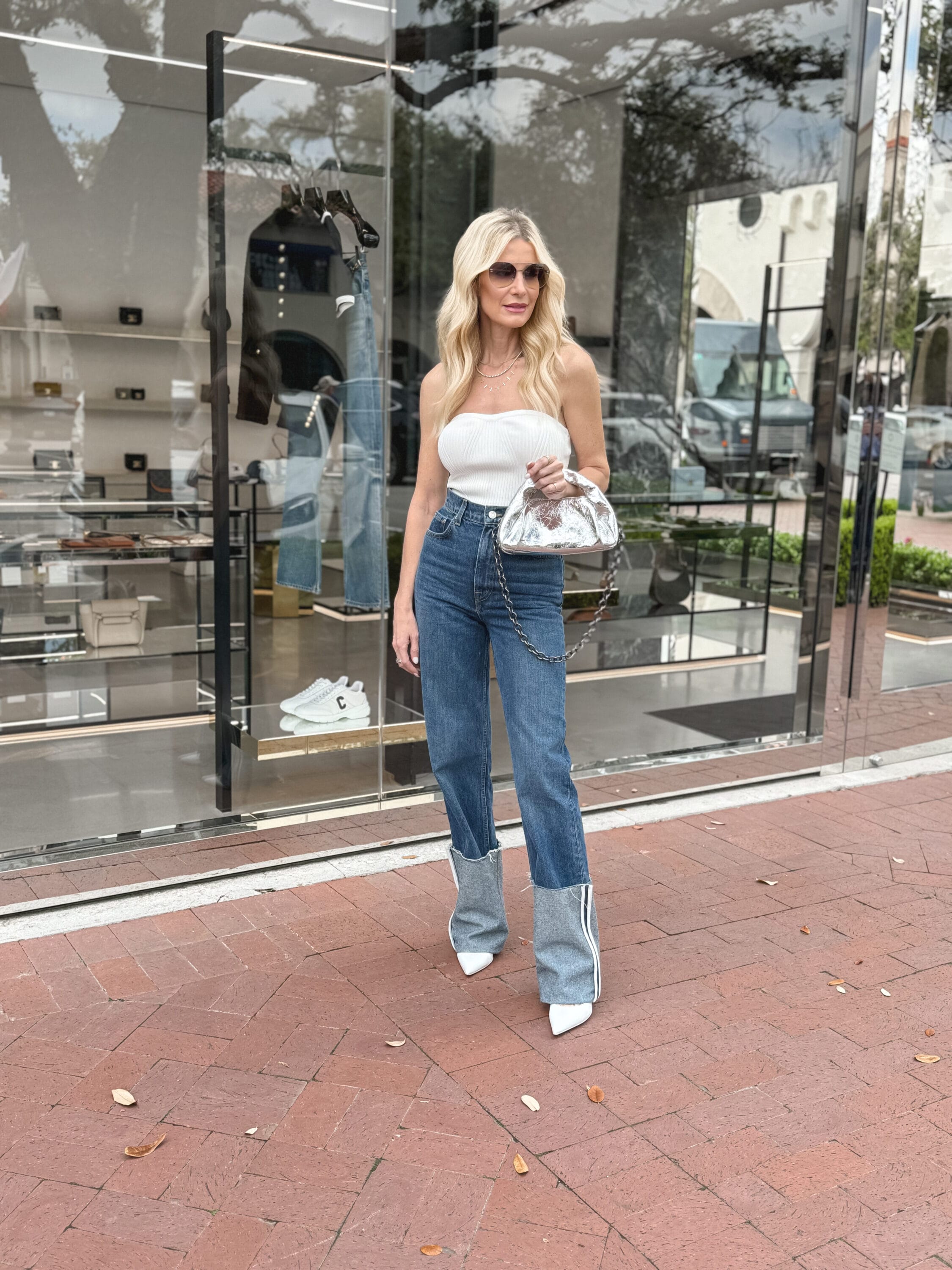 Over 40 fashion ICON wearing cuffed denim with a white strapless top and white stilettos.