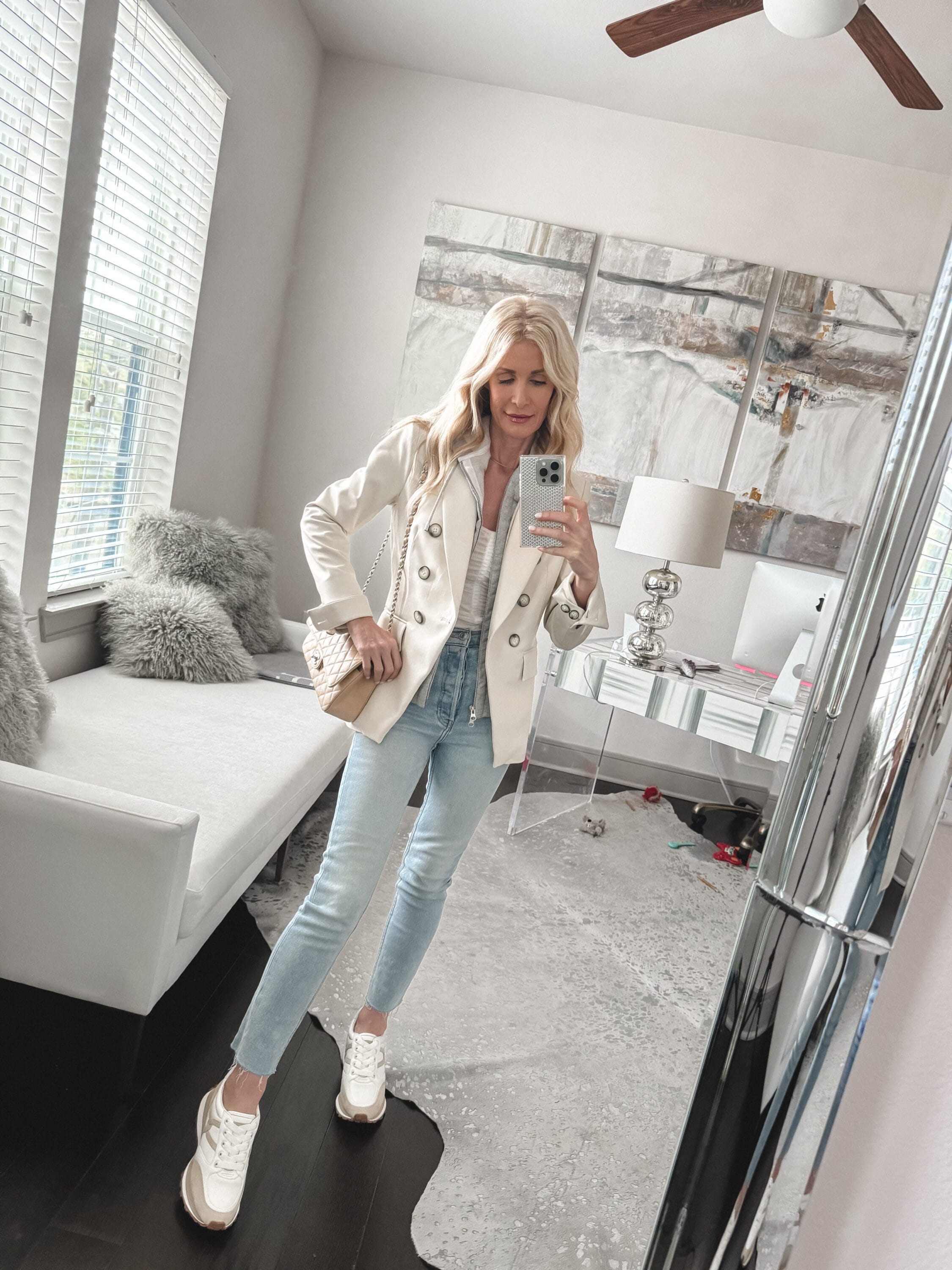 Dallas fashion blogger over 40 wearing high waisted light wash jeans with a white blazer and veronica beard sneakers as one of 3 examples of how to look chic in sneakers.