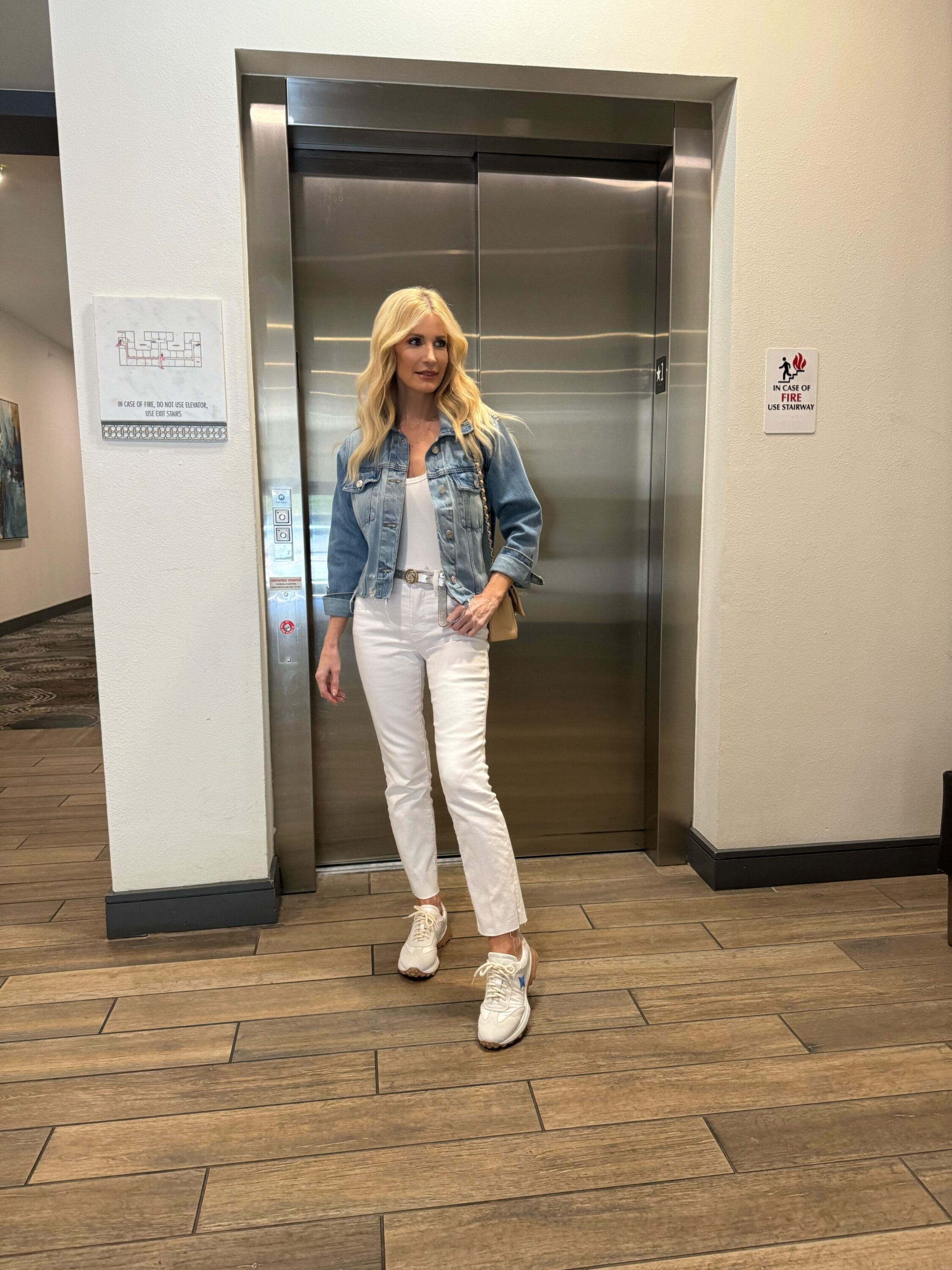 Over 40 fashion blogger showcasing how to wear white jeans with a cropped denim jacket a stylish sneakers.
