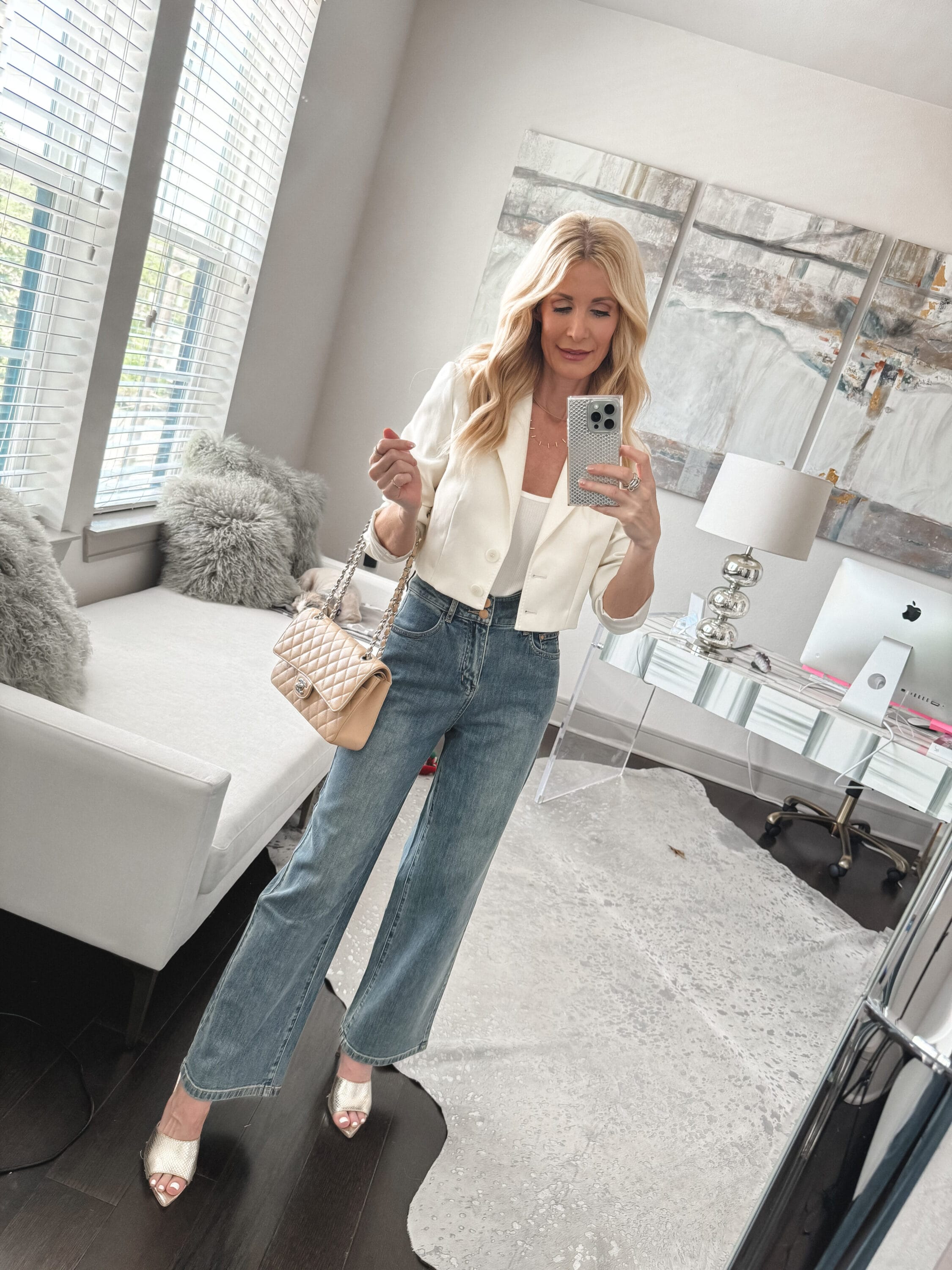 Over 40 fashion icon from Dallas wearing wide leg jeans with an ivory cropped jacket and gold mules as a stylish spring look.