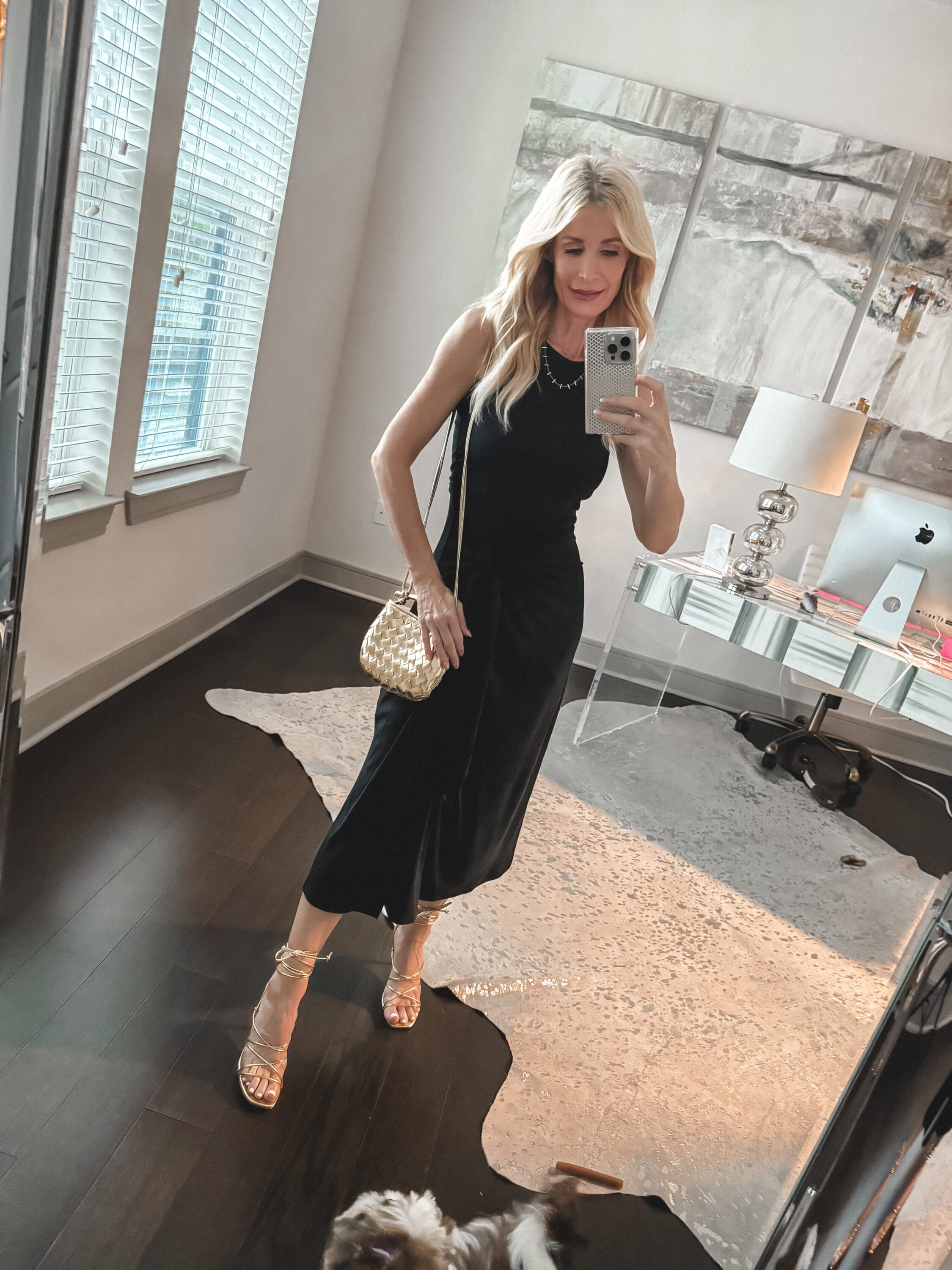 Dallas woman over 40 wearing a black tie waist midi dress with gold lace up heels.