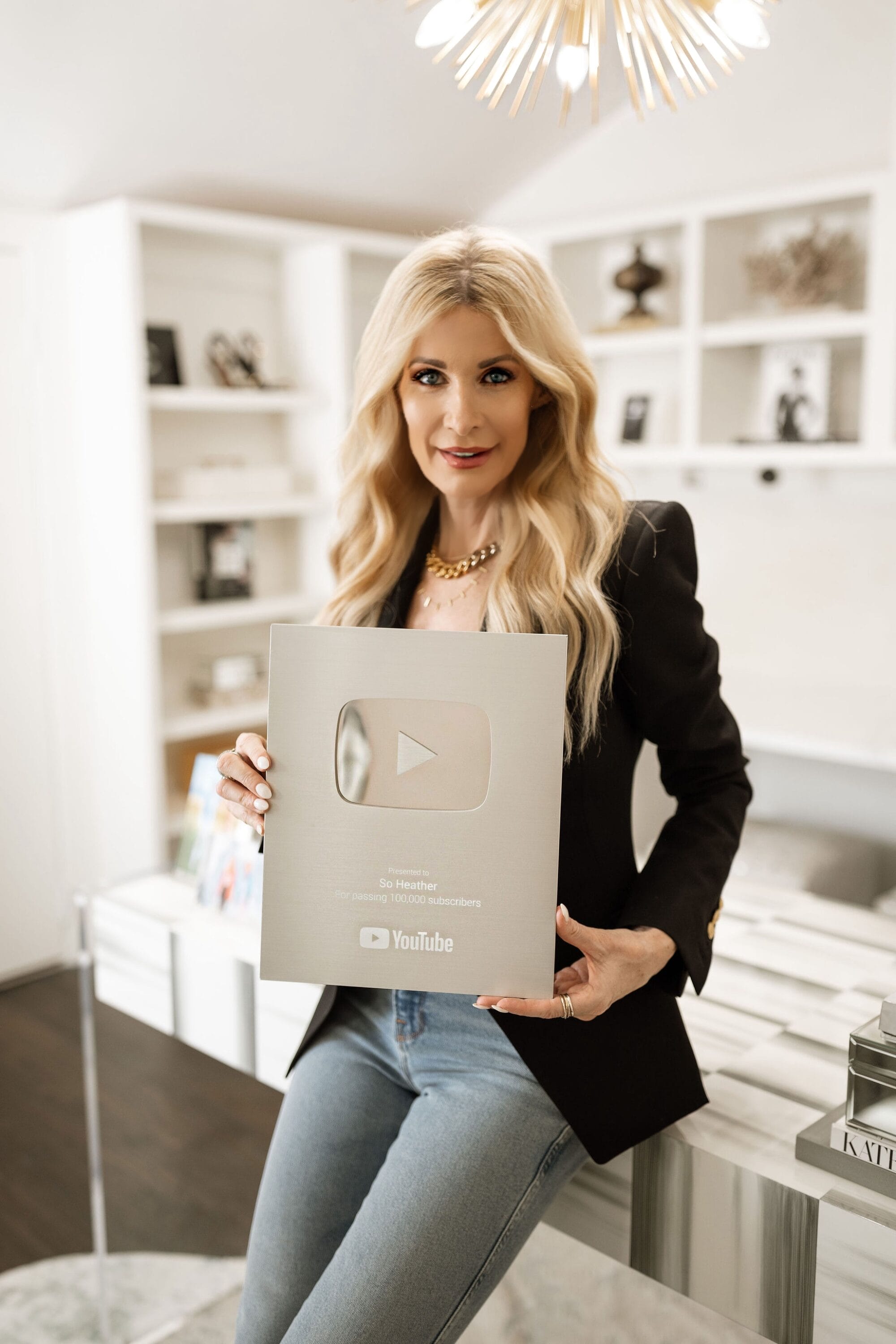 Over 40 fashion blogger showing her 100,000 YouTube subscriber award surrounded by her new home office decor.