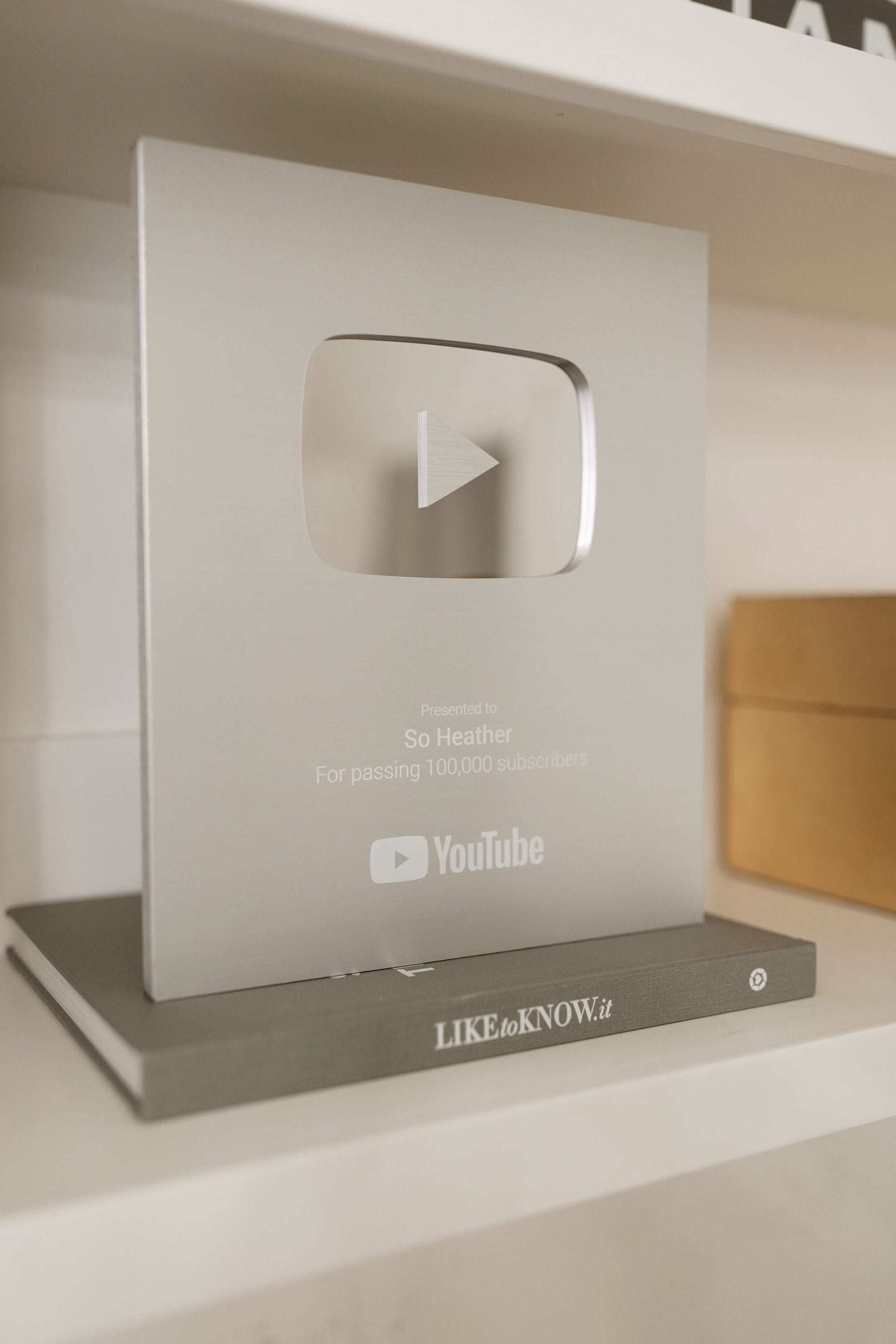 Close up shot of an award for 100,000 subscribers from YouTube for SoHeather.