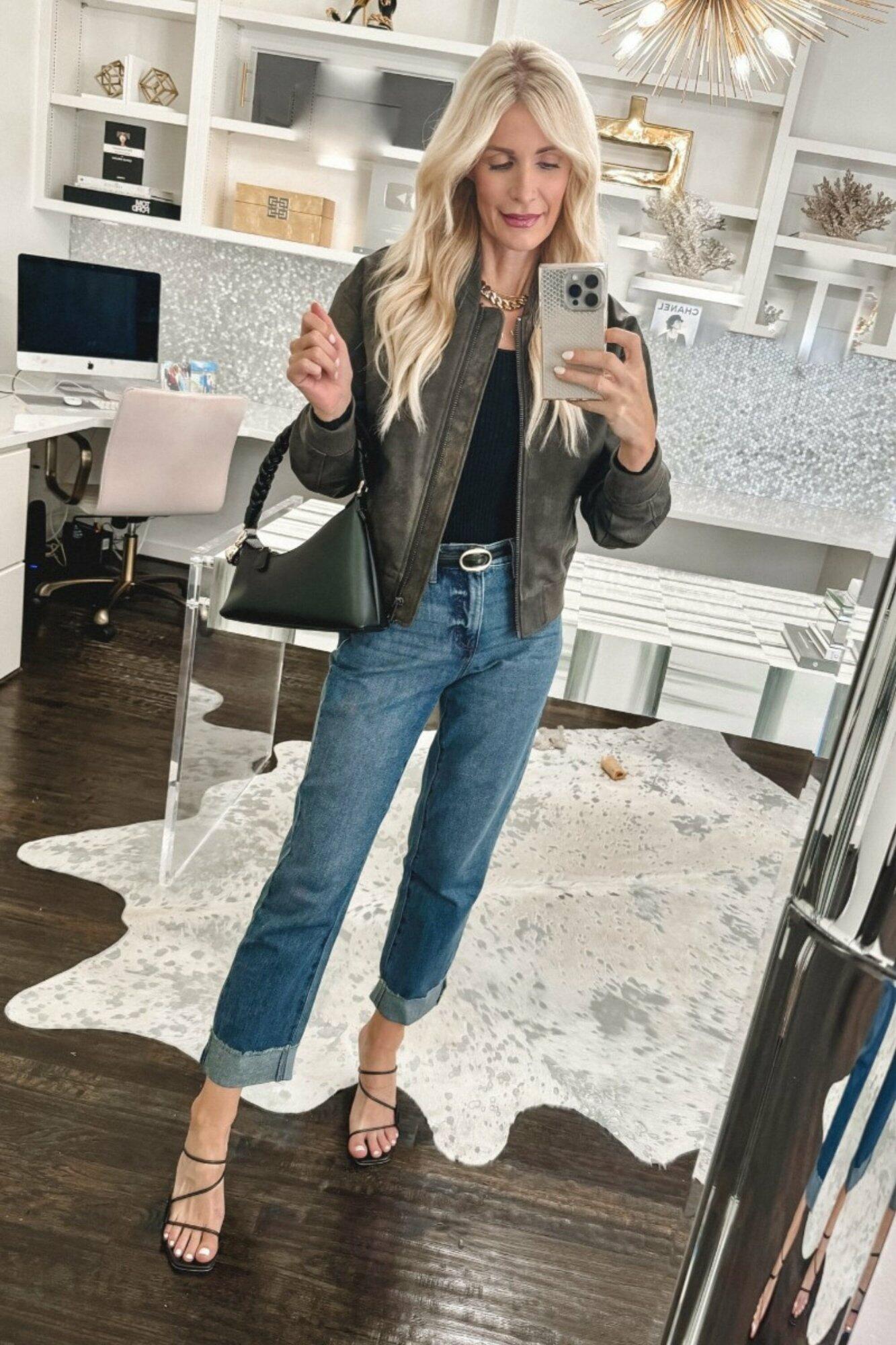 Dallas fashion influencer for women over 40 wearing a distressed matte bomber jacket with cuffed jeans as 2 examples of under $50 pieces for fall.