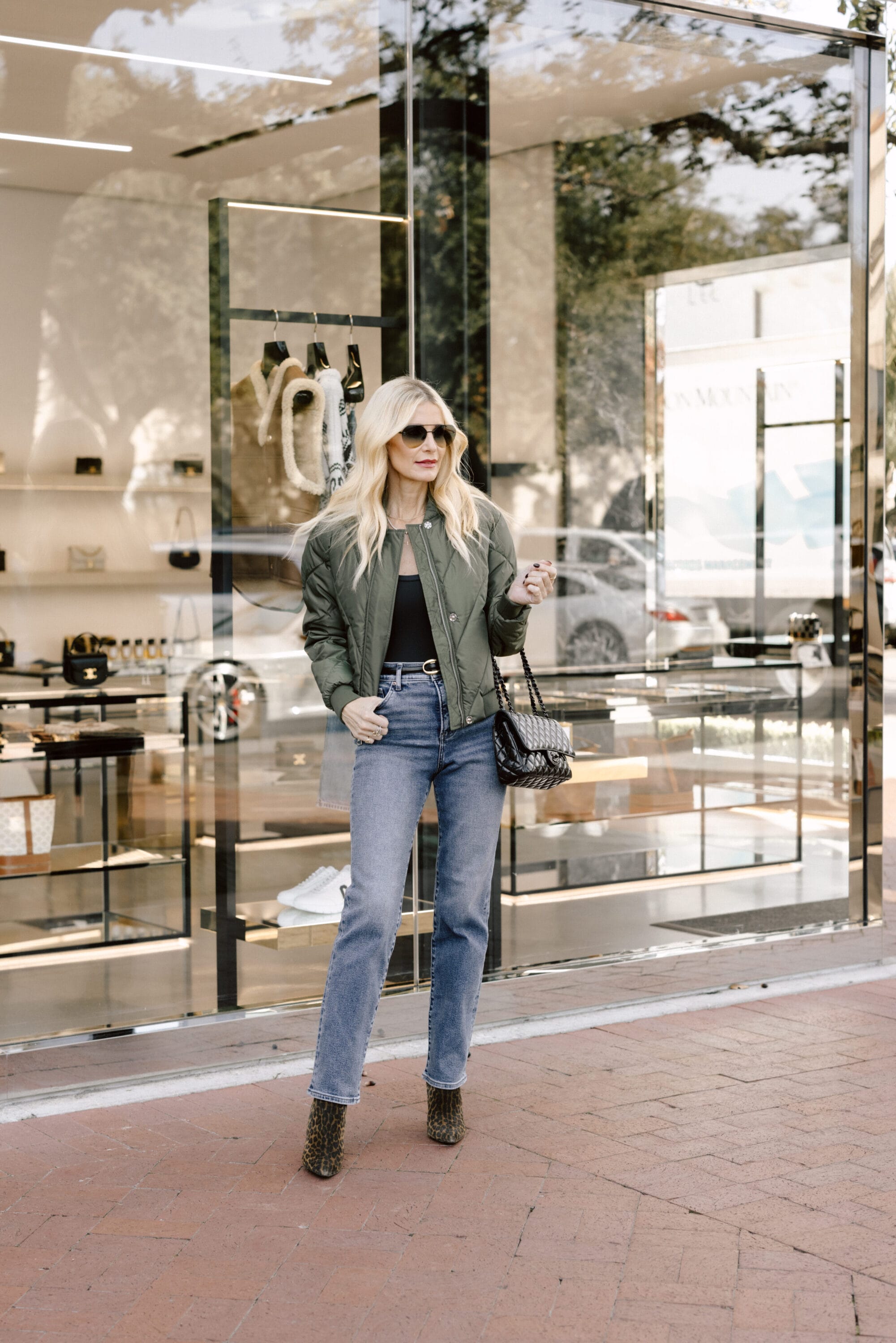 Dallas woman over 40 wearing straight leg jeans with leopard booties and sage green bomber jacket.