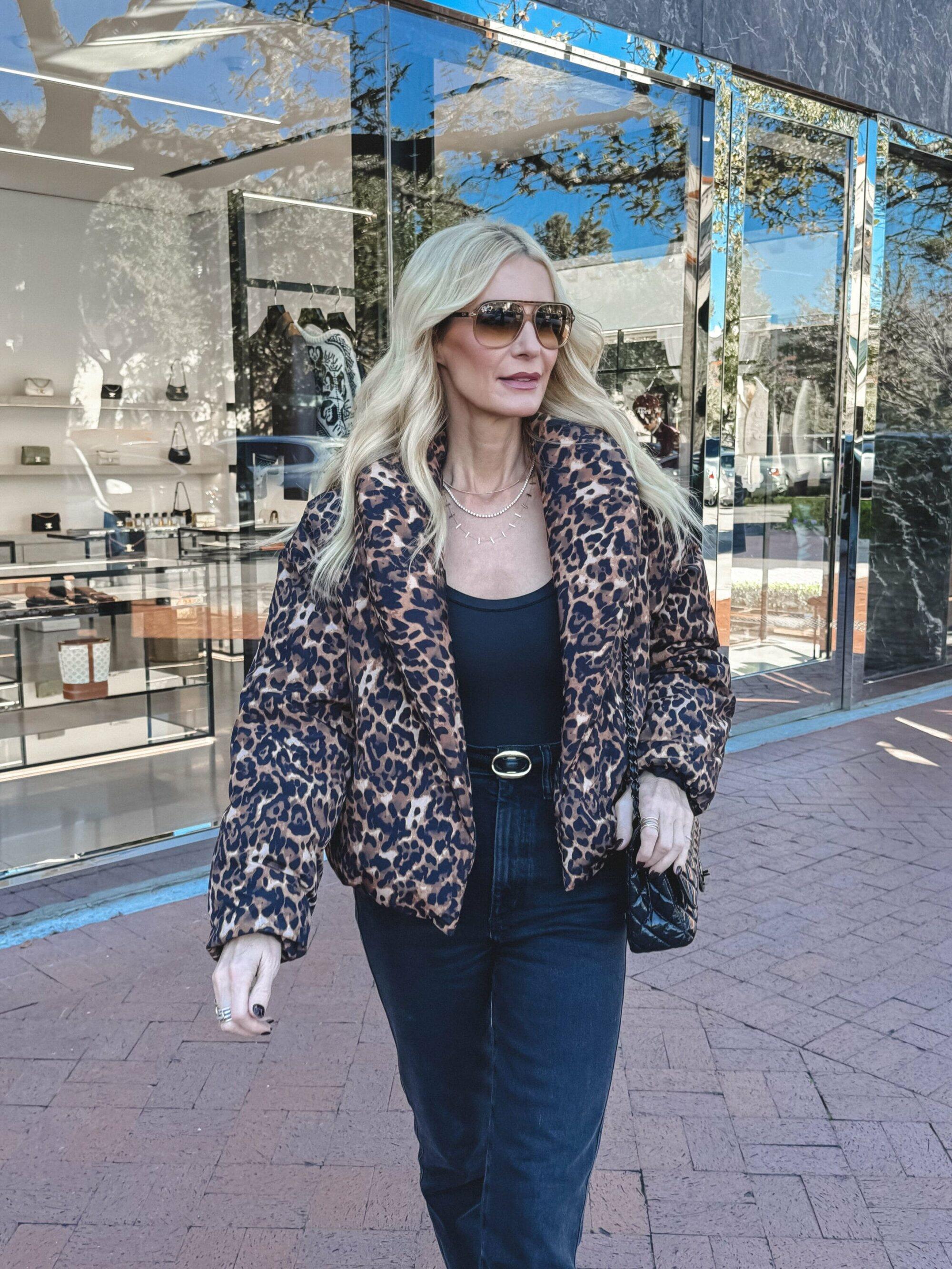 Close up shot of an over 40 Dallas fashion influencer wearing a leopard puffer jacket with black straight leg jeans.
