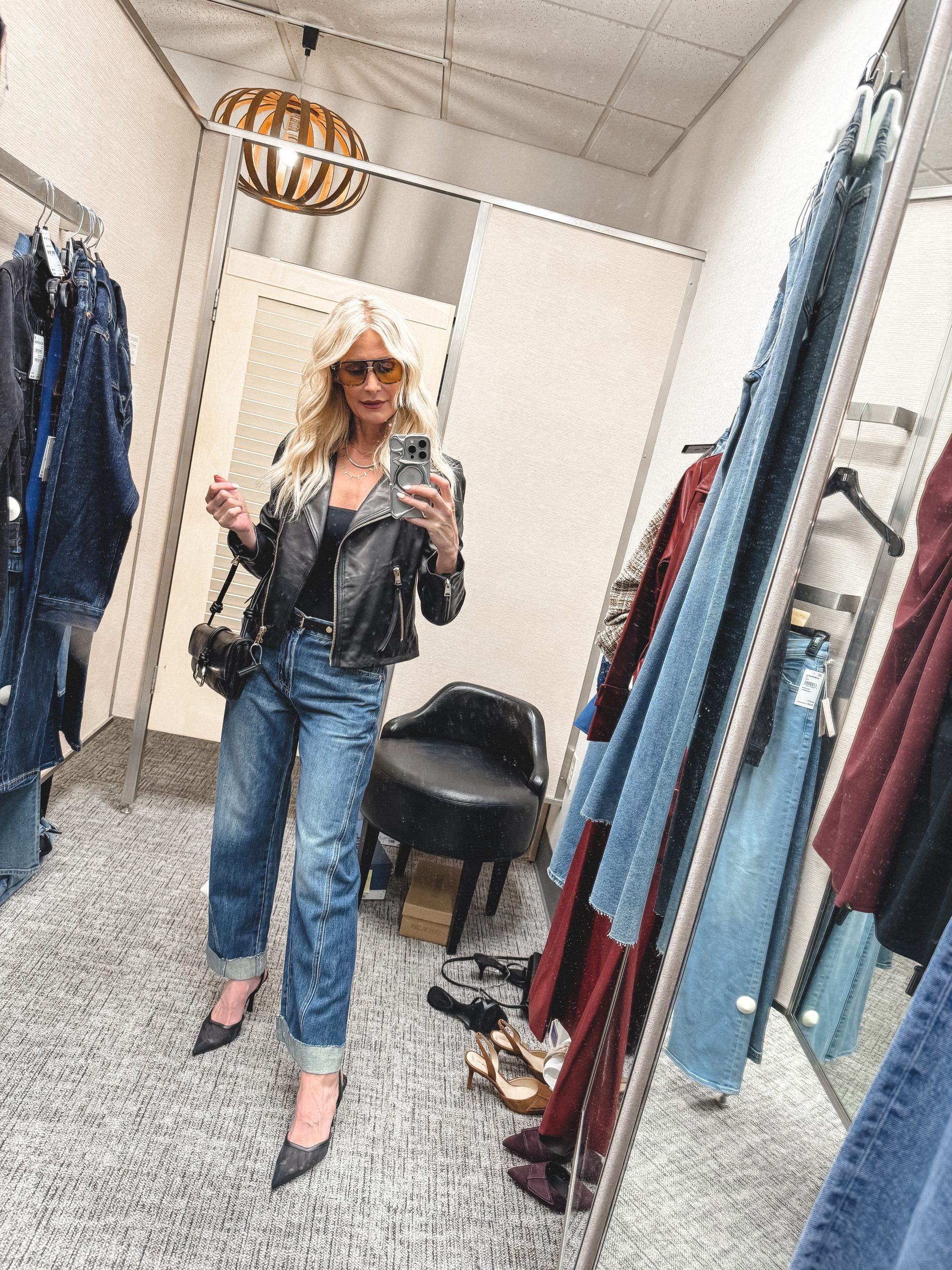 Over 40 fashion stylist wearing a cropped leather jacket with cuffed jeans and mesh heels.