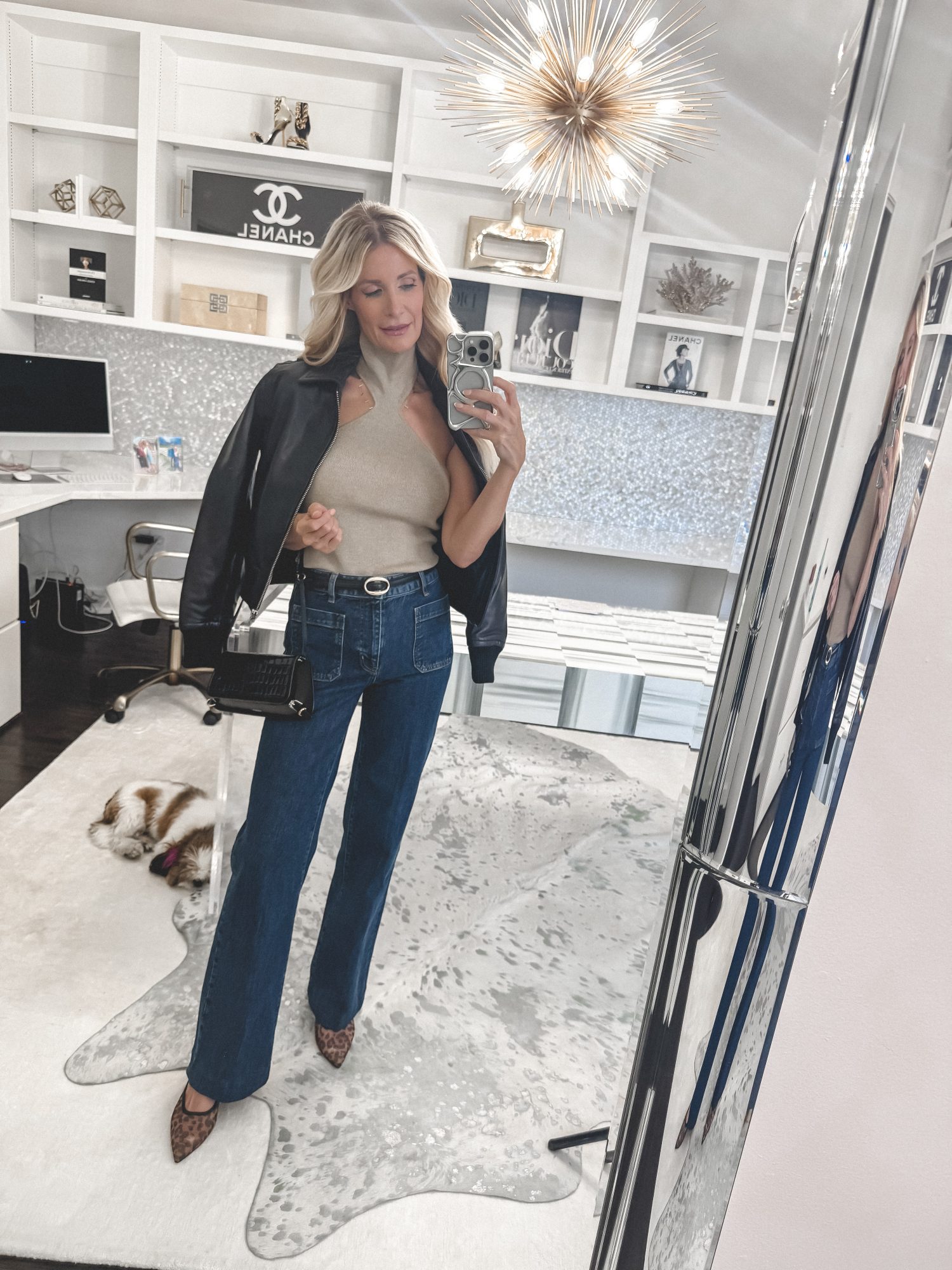 Over 40 fashion influencer wearing a highneck top with wide leg jeans and animal print heels.