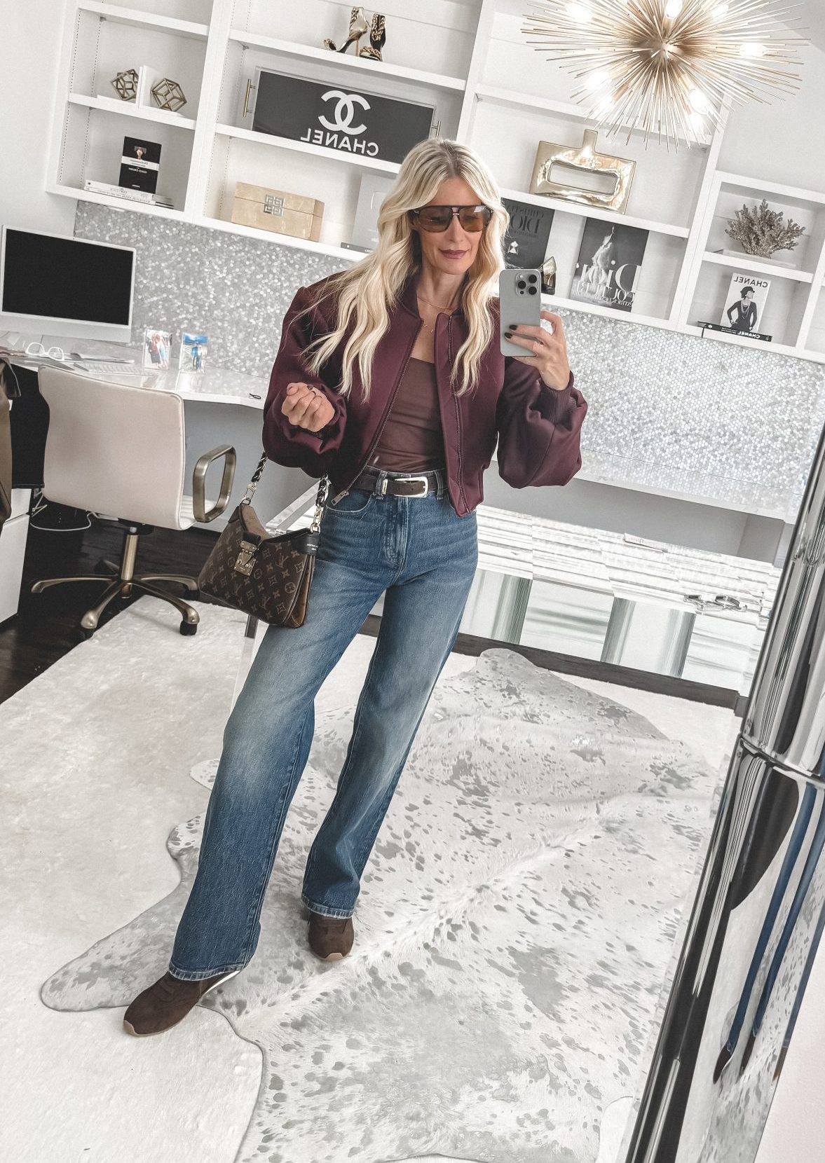Dallas fashion blogger wearing a burgundy bomber jacket with wide leg jeans and slim sneakers.